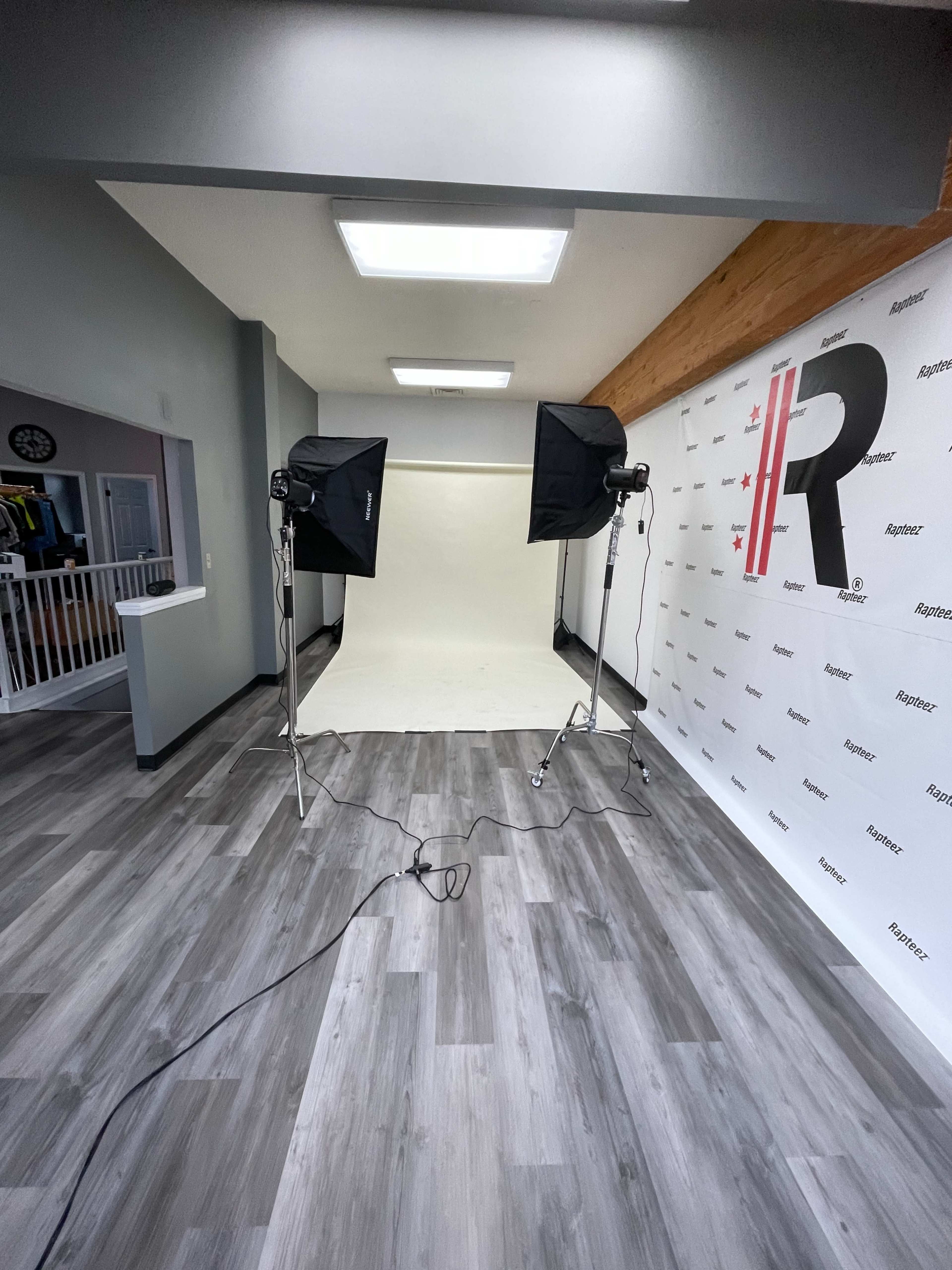 A photography studio setup with a seamless background, two softbox lights, and a floor with wooden laminate.