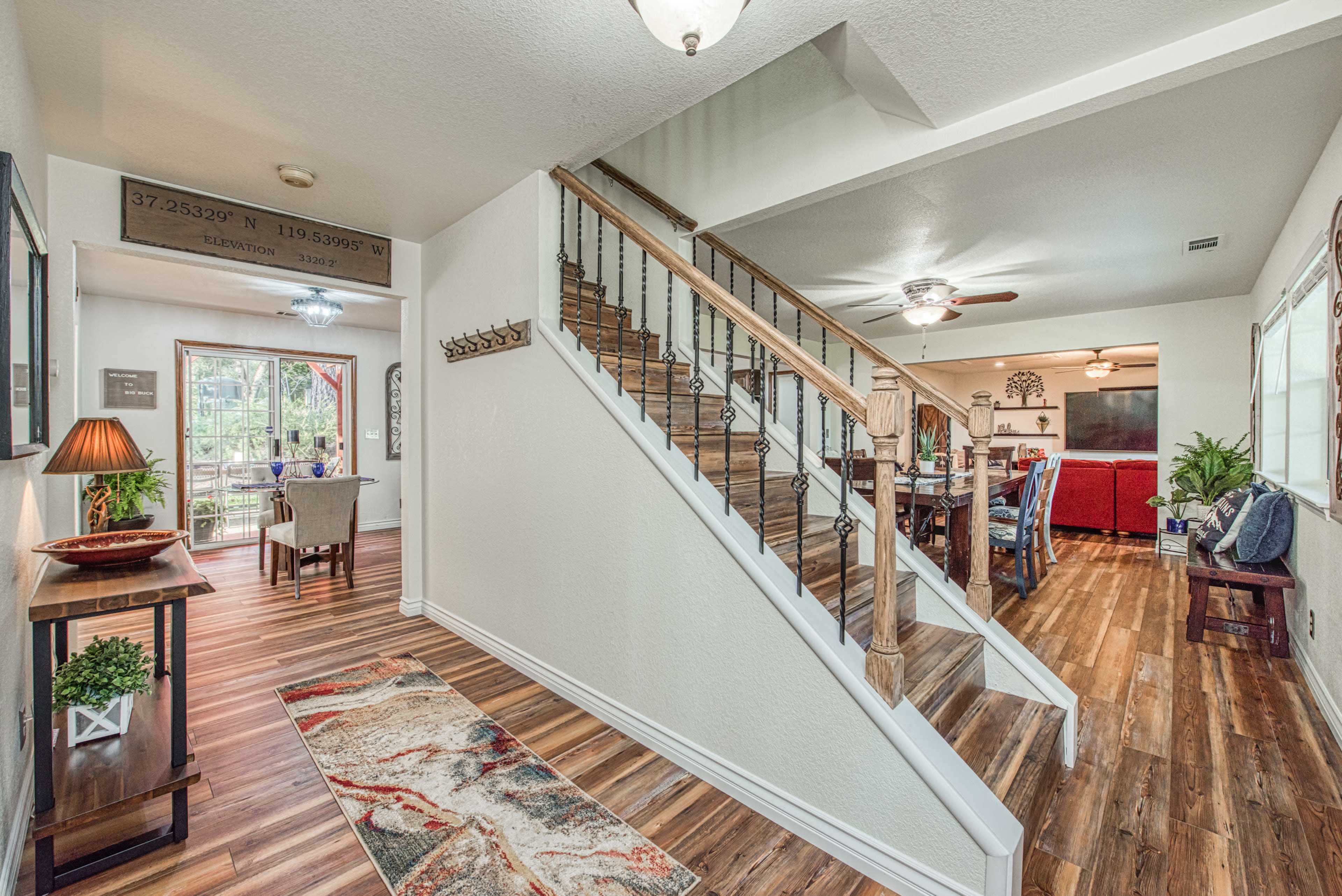 A well-lit entryway with a staircase leading to an upper level, and a dining area visible in the background.