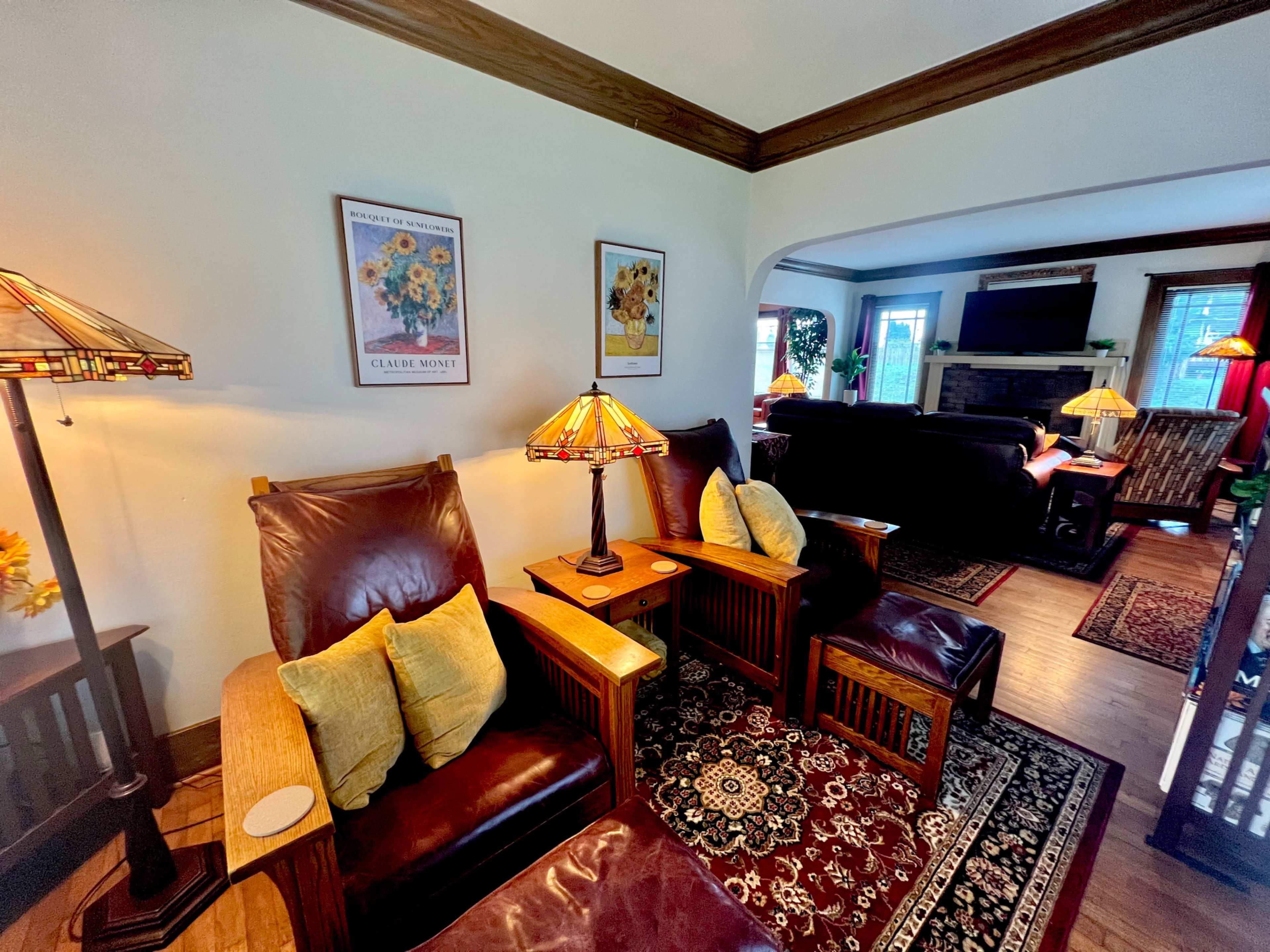A cozy living room with leather chairs, decorative lamps, and artwork on the walls.