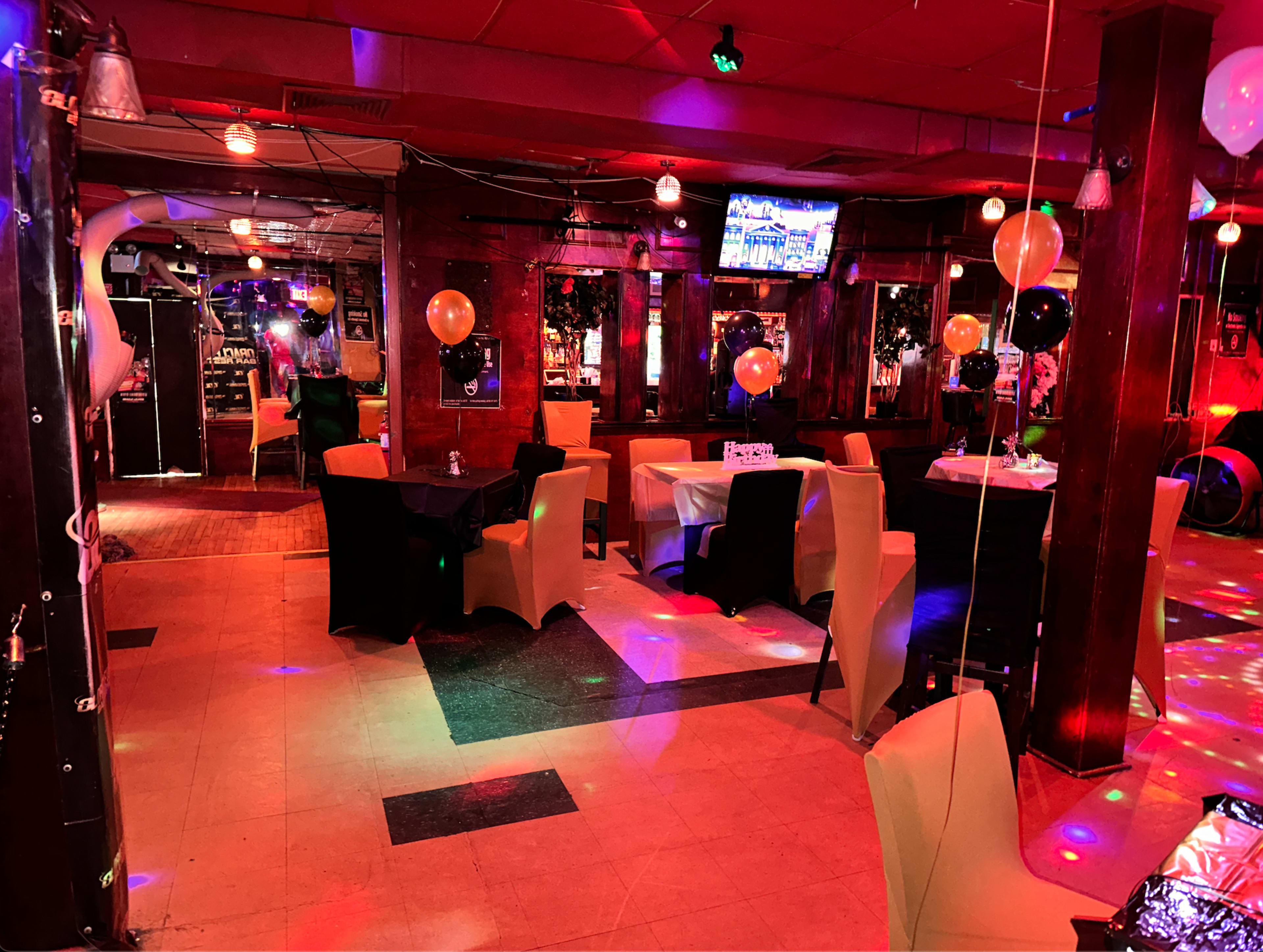 A decorated restaurant interior with tables, chairs, and colorful lighting effects.