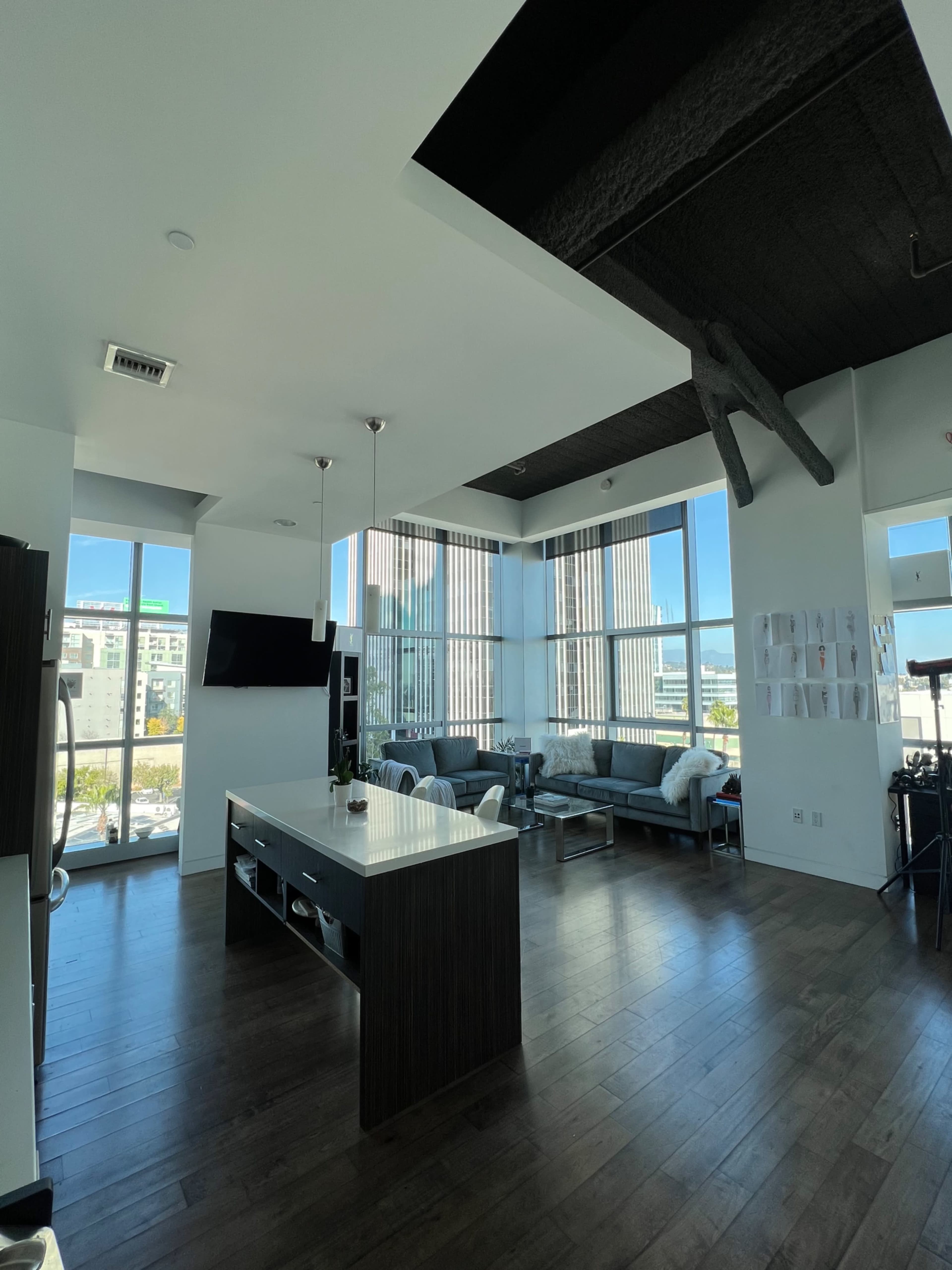 A modern, open-concept living space featuring large windows, sleek furniture, and hardwood floors.