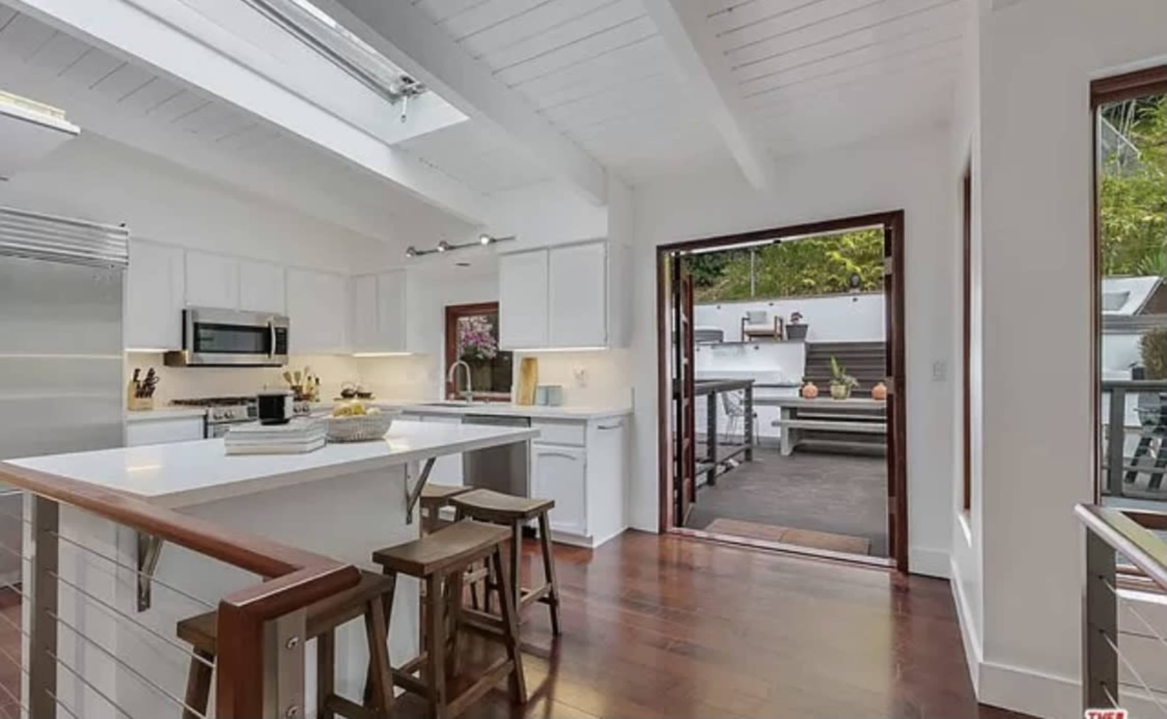 A modern kitchen with white cabinetry, stainless steel appliances, and a sliding door that opens to an outdoor patio area.
