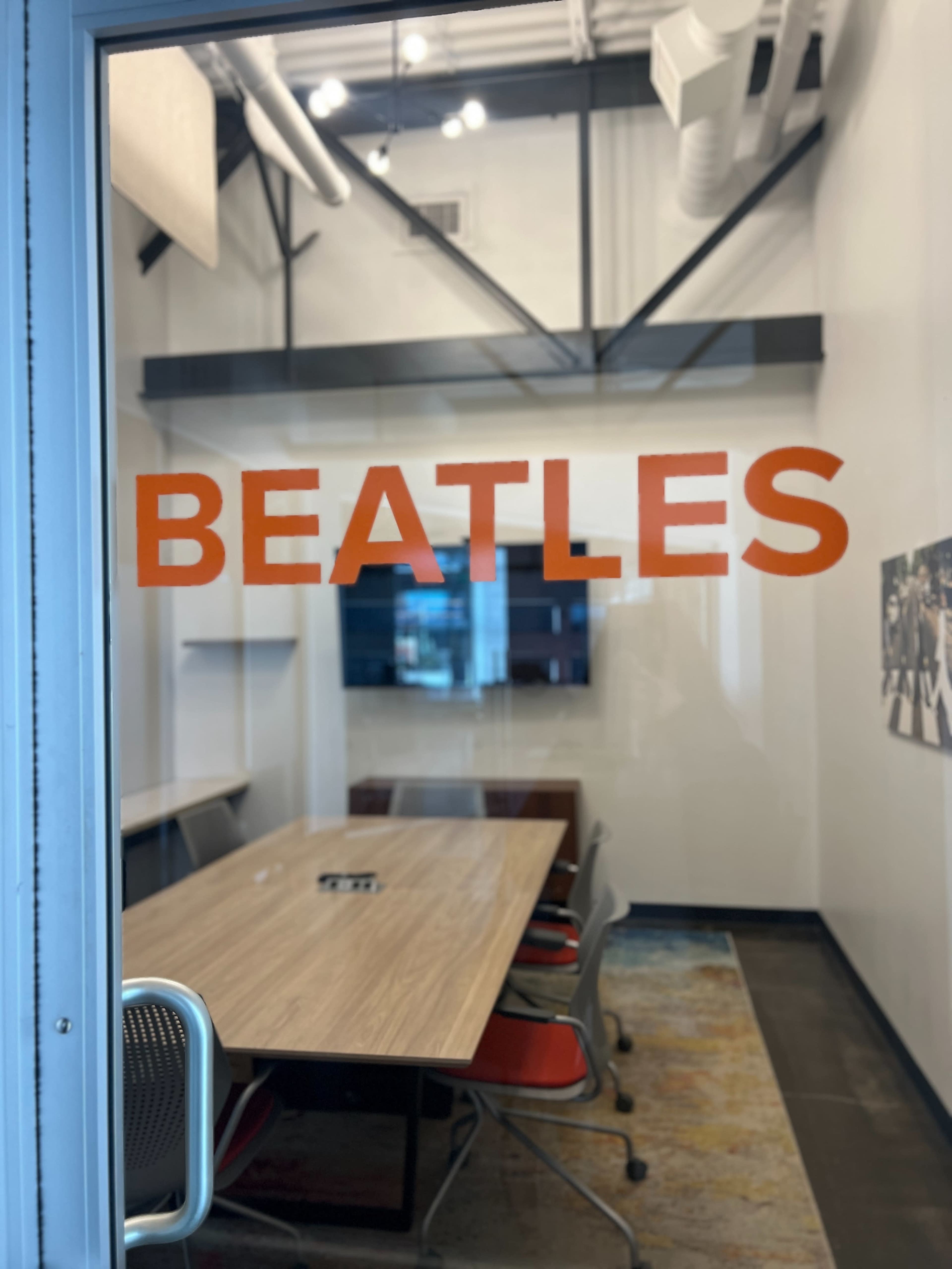 A conference room door displays the word "BEATLES" in large, orange letters.