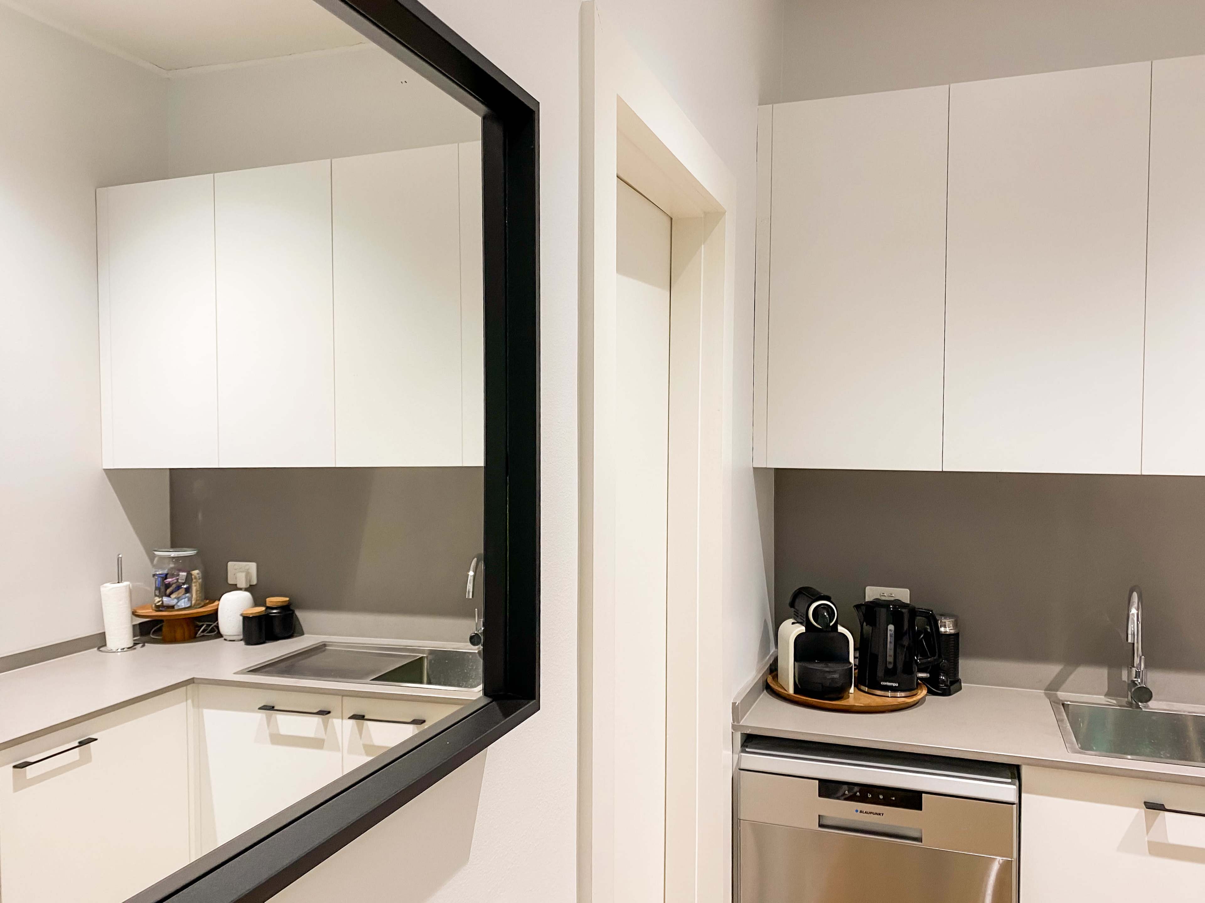 A modern kitchen with white cabinetry, a sink, and various kitchen appliances visible on the countertop.