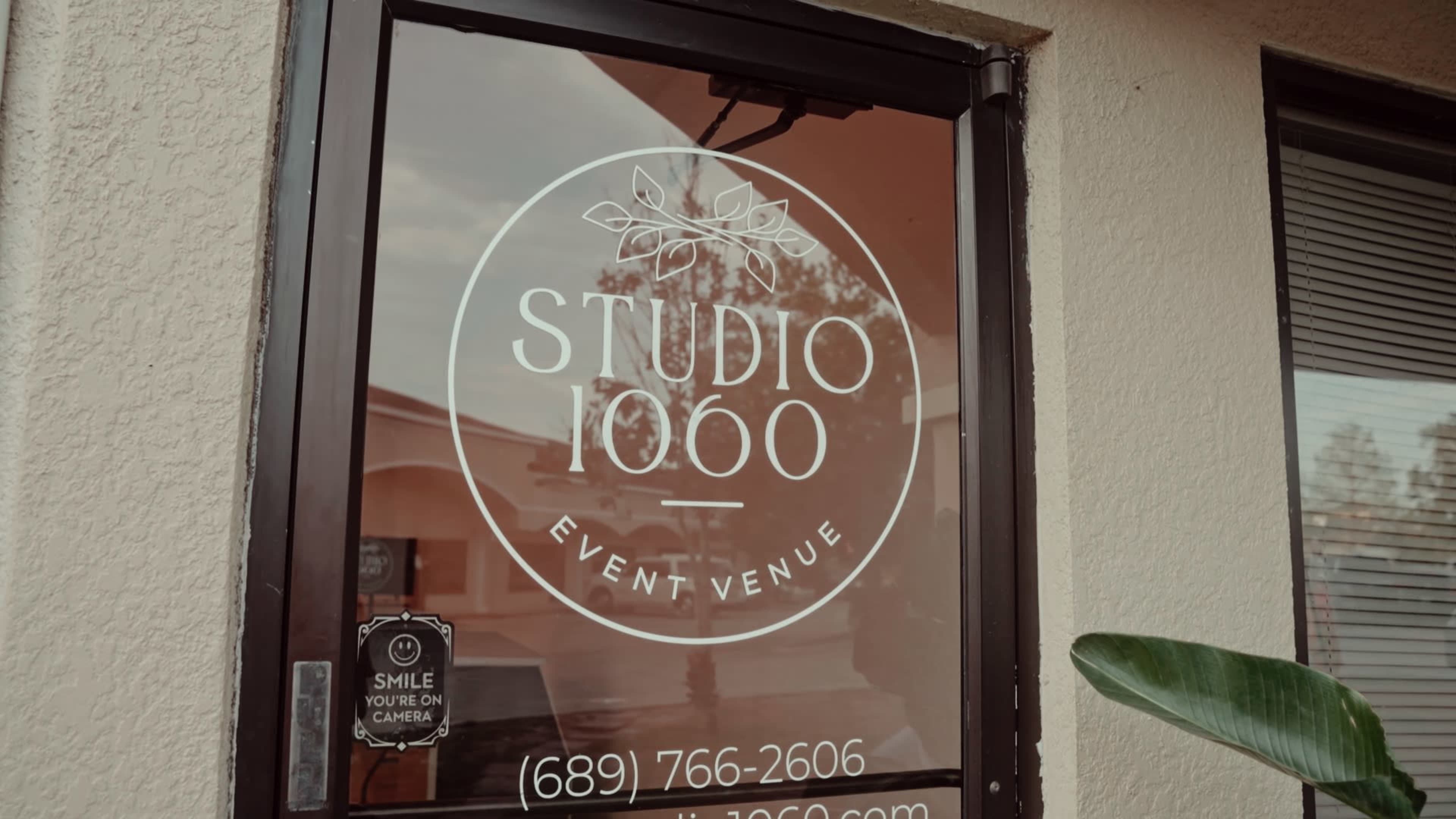 A glass door with the logo and contact information for Studio 1060, an event venue.