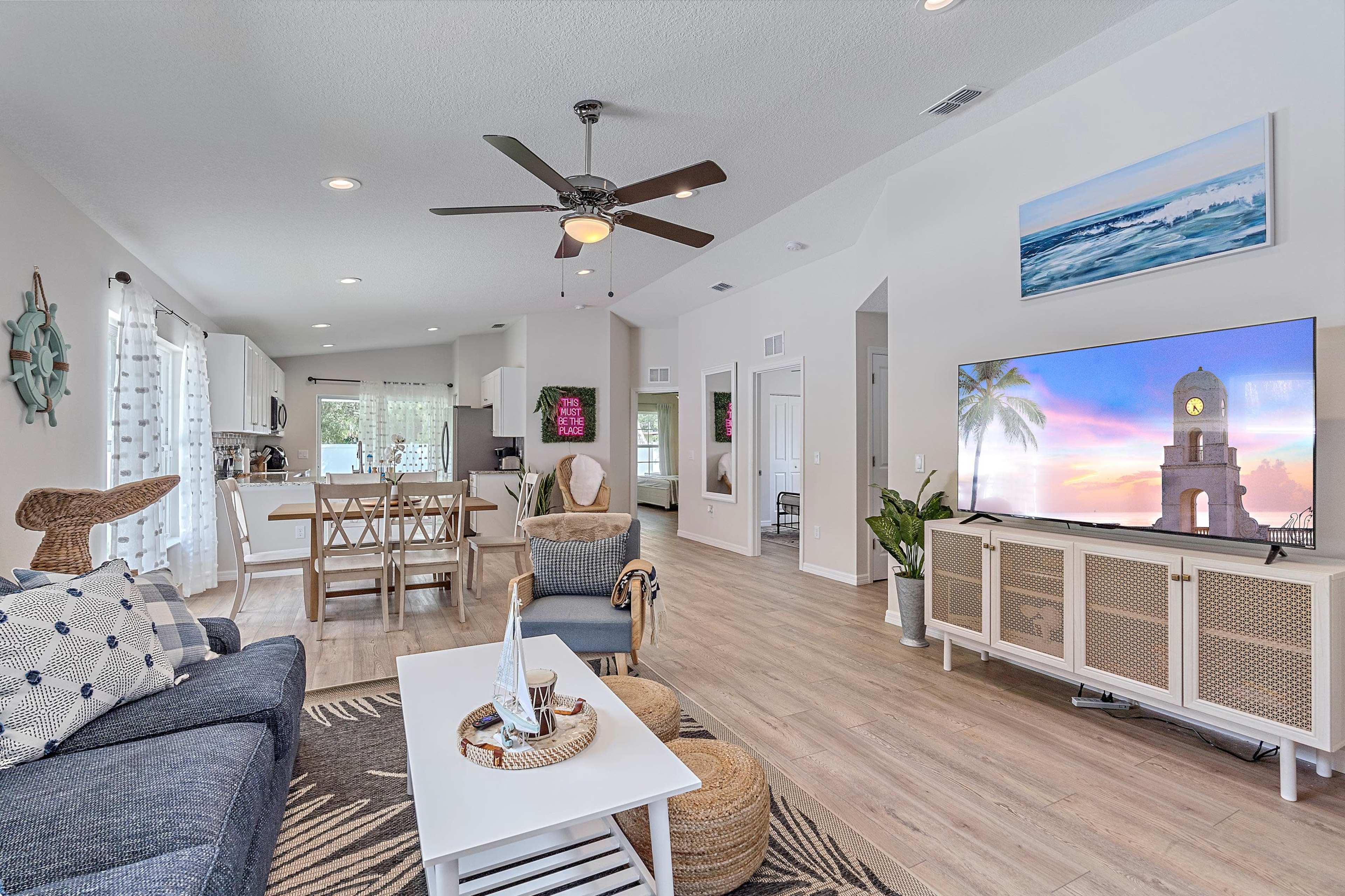 The open-concept living area features a comfortable seating arrangement, a television, and a dining space, all bathed in natural light.