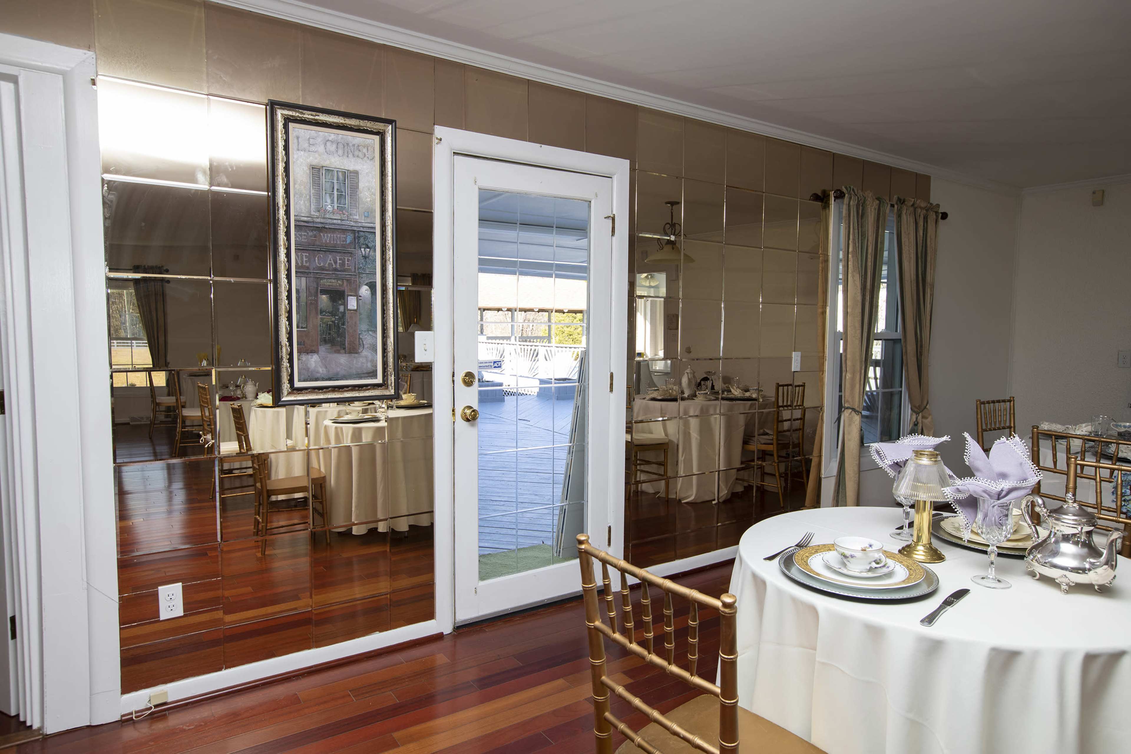 A dining area with a mirrored wall, a table set for a meal, and a door leading to an outdoor space.
