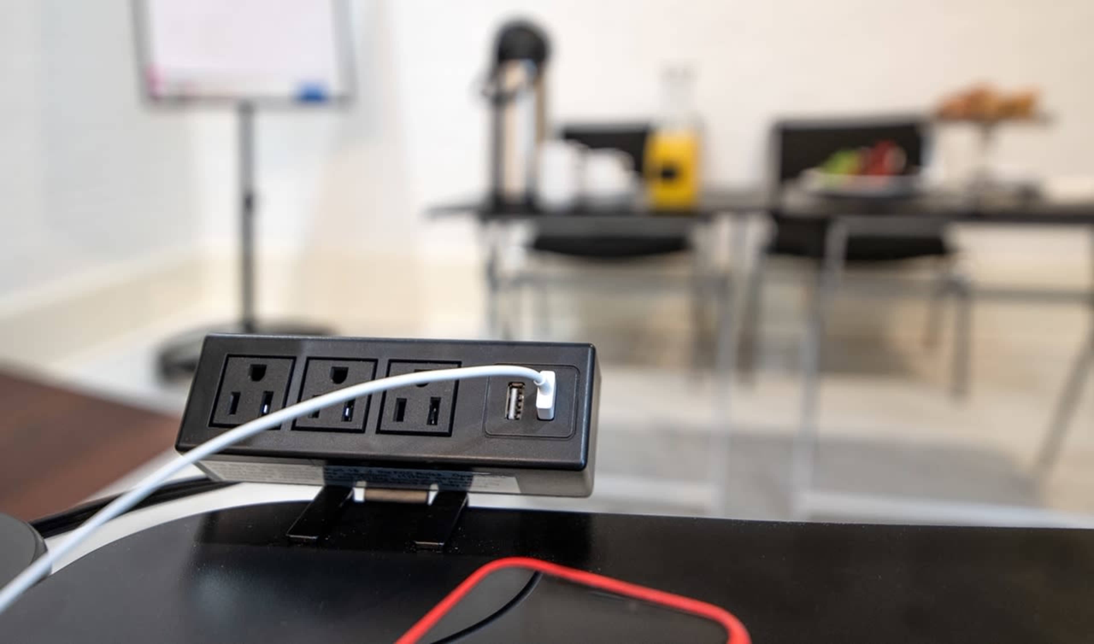 A table set with refreshments is visible in the background, while a power outlet with multiple ports is in the foreground.
