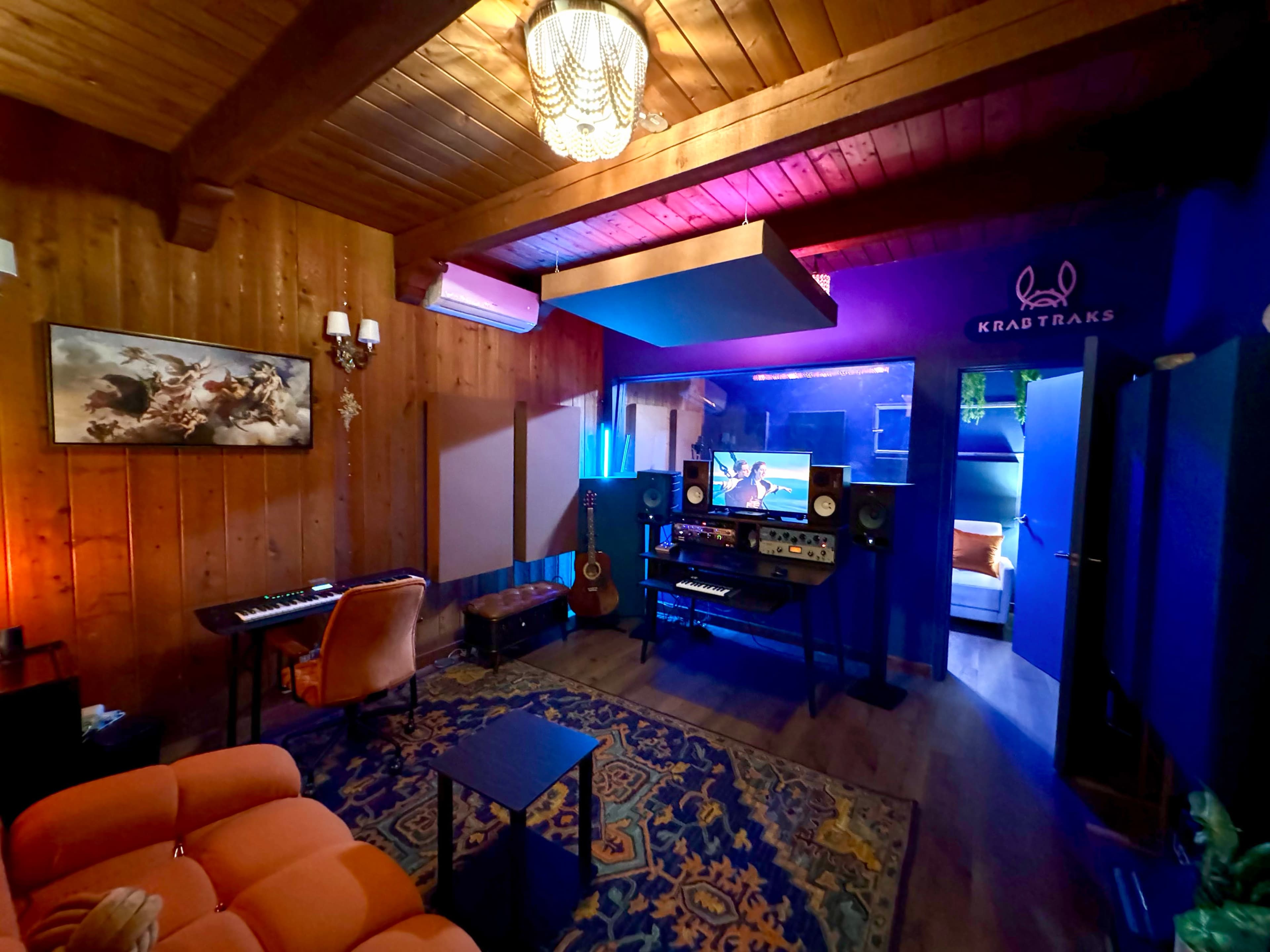 A music studio with wooden walls, a keyboard, and various sound equipment arranged in a cozy atmosphere.