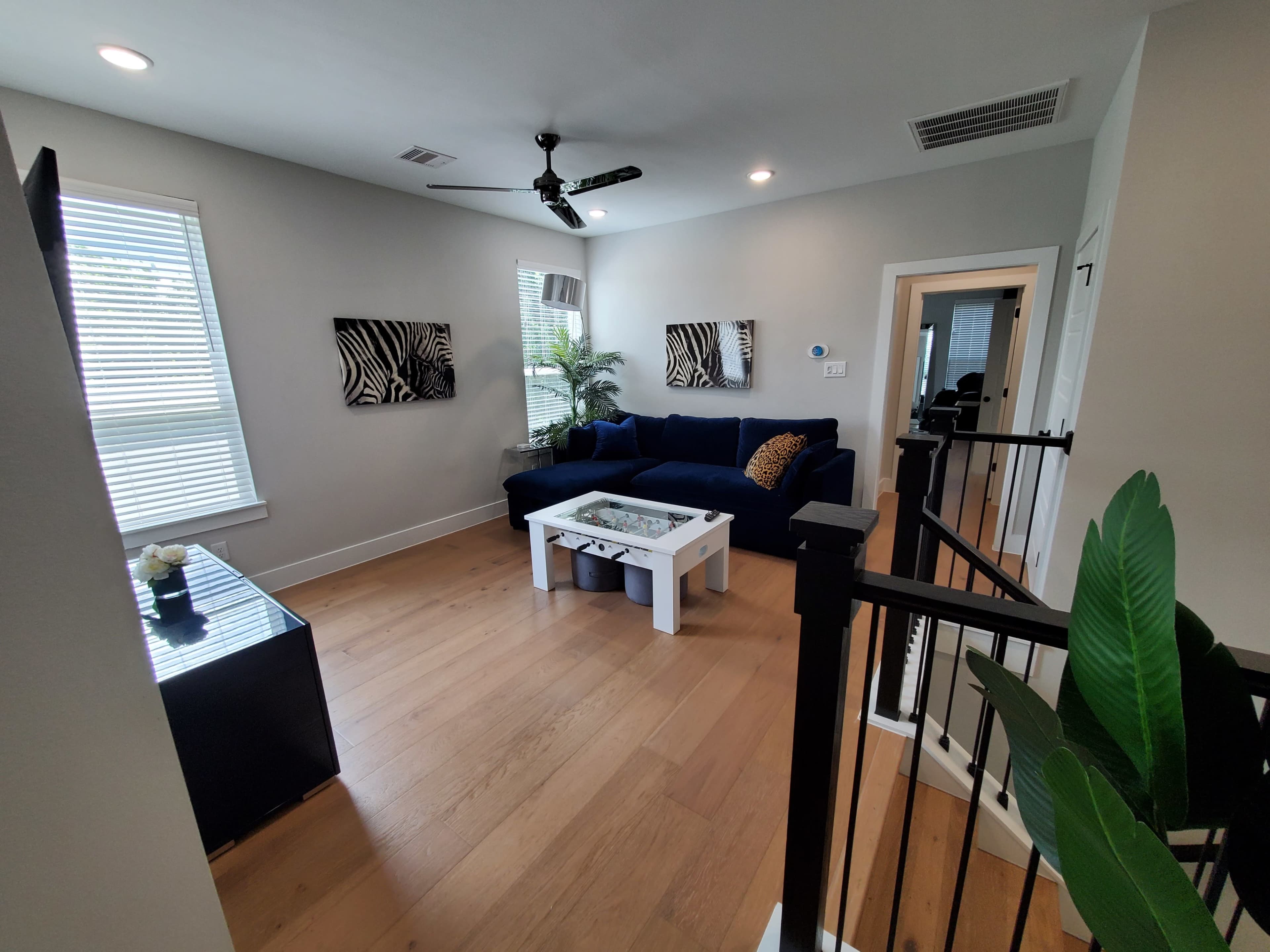 A modern living room featuring a blue sectional sofa, a white coffee table, and decorative wall art, with natural light coming through the windows.