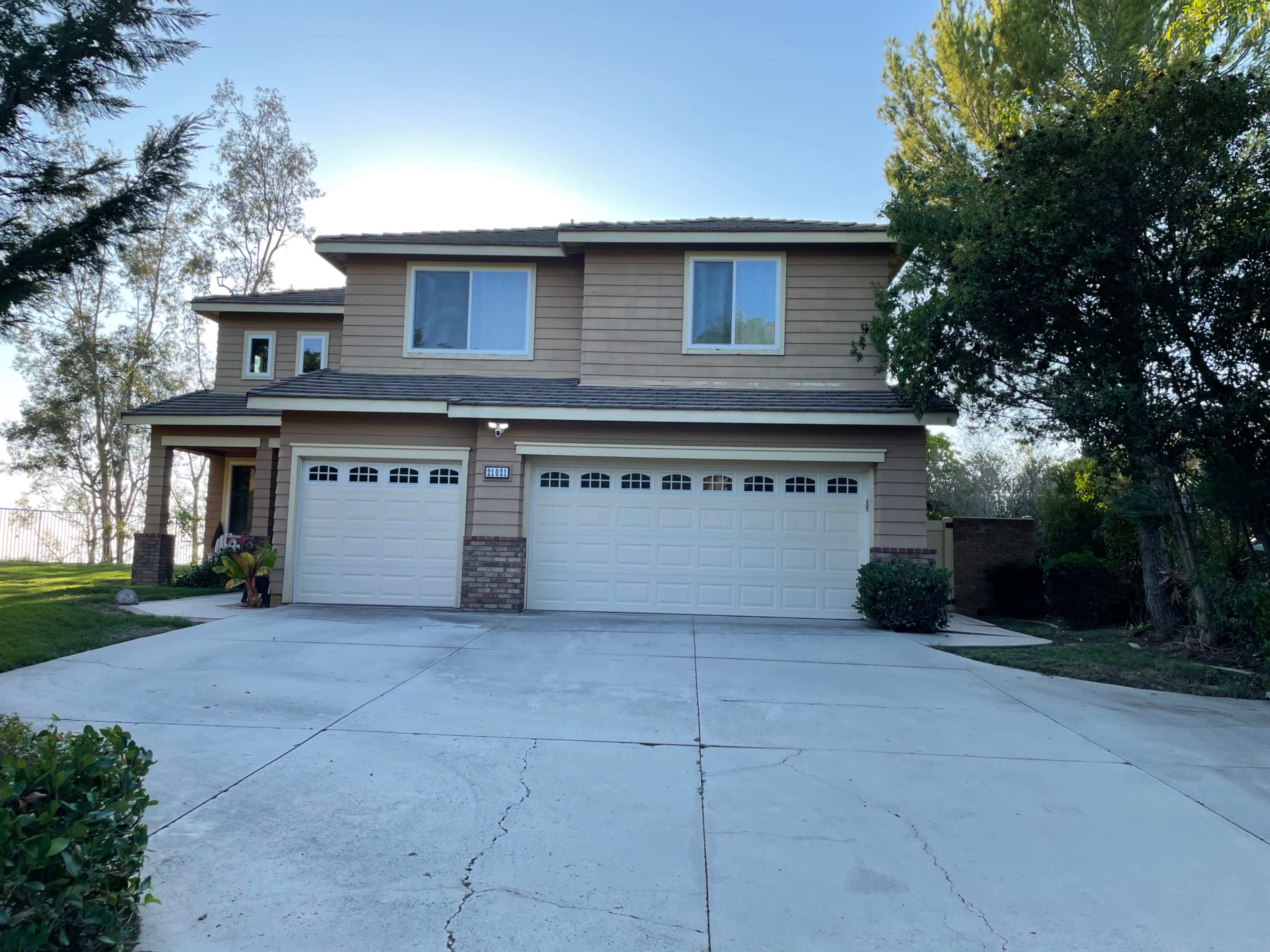 A two-story house with a front porch, a three-car garage, and a landscaped yard.