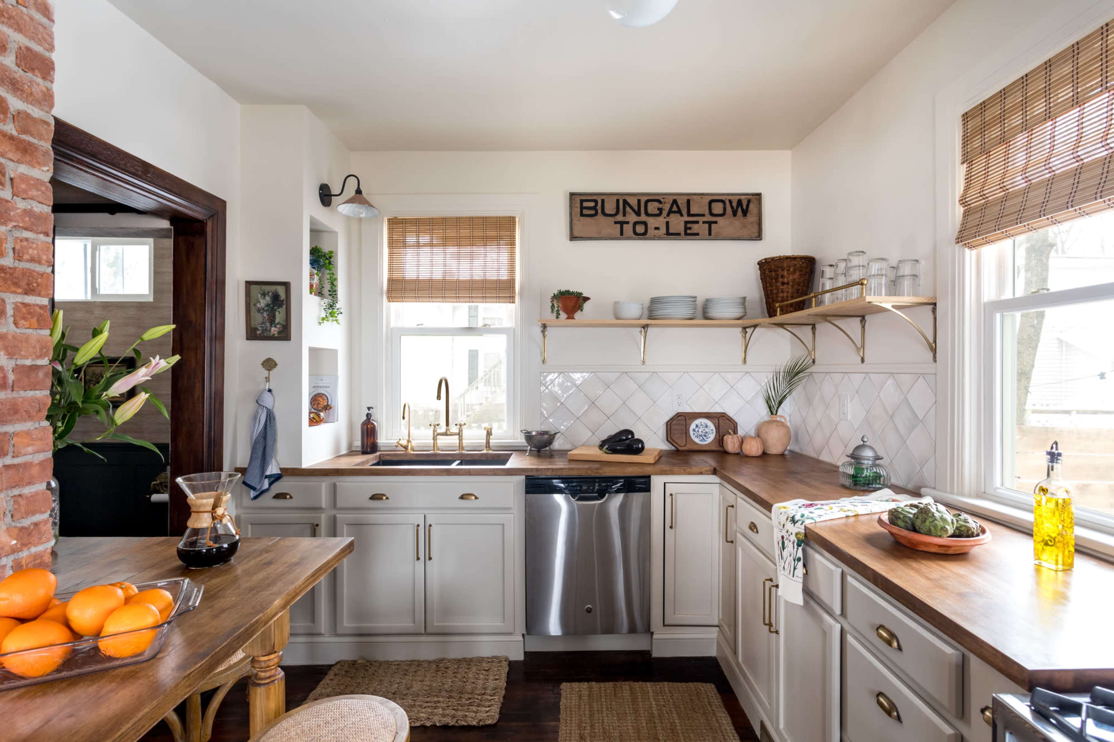 A kitchen features a mix of white cabinets, wooden countertops, and open shelving with decorative items.