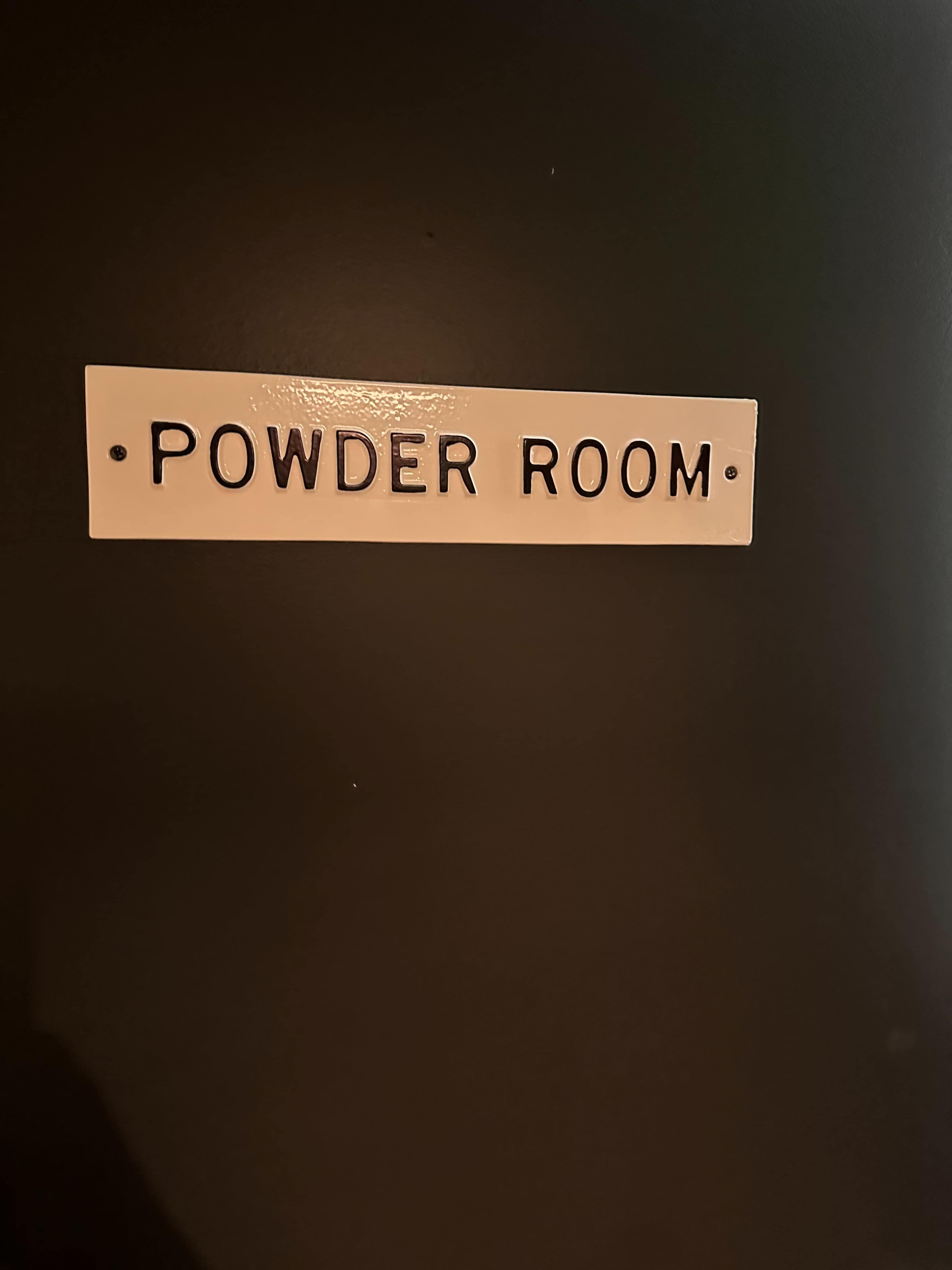 A sign labeled "POWDER ROOM" is displayed on a dark wall.