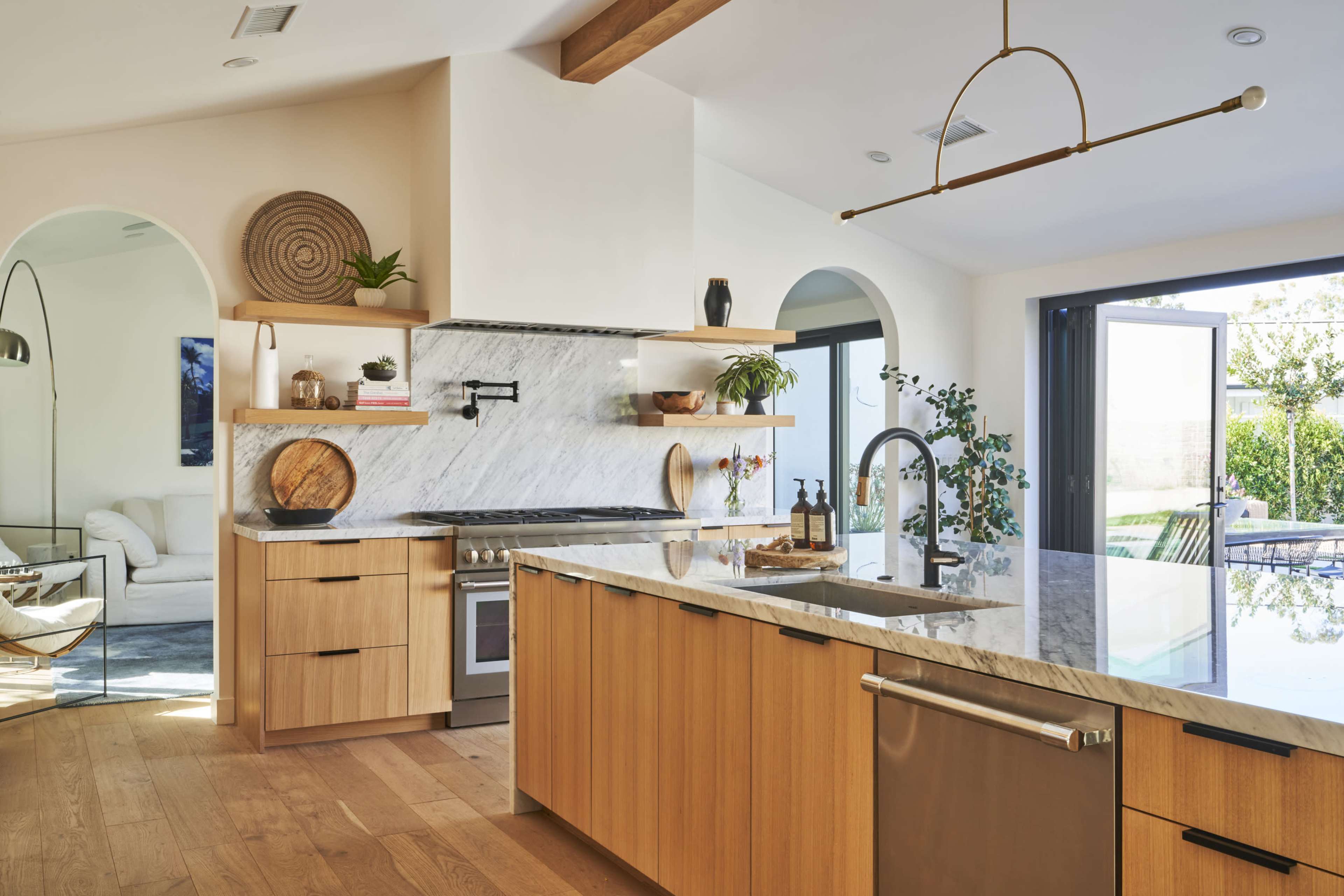 The kitchen features wooden cabinetry, a marble countertop, and a large window overlooking a patio.