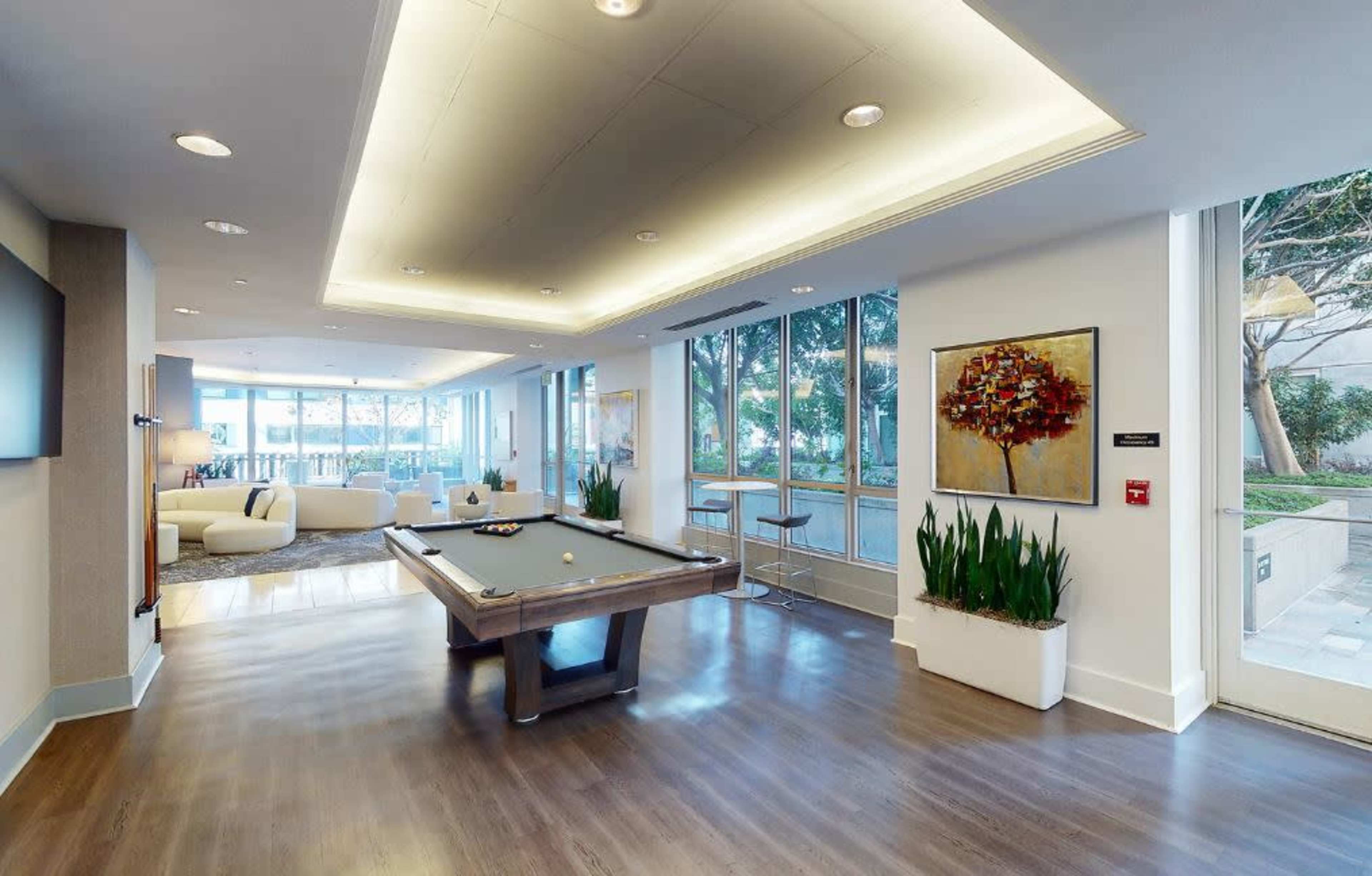 A modern lounge area featuring a pool table, large windows, and contemporary seating arrangements.