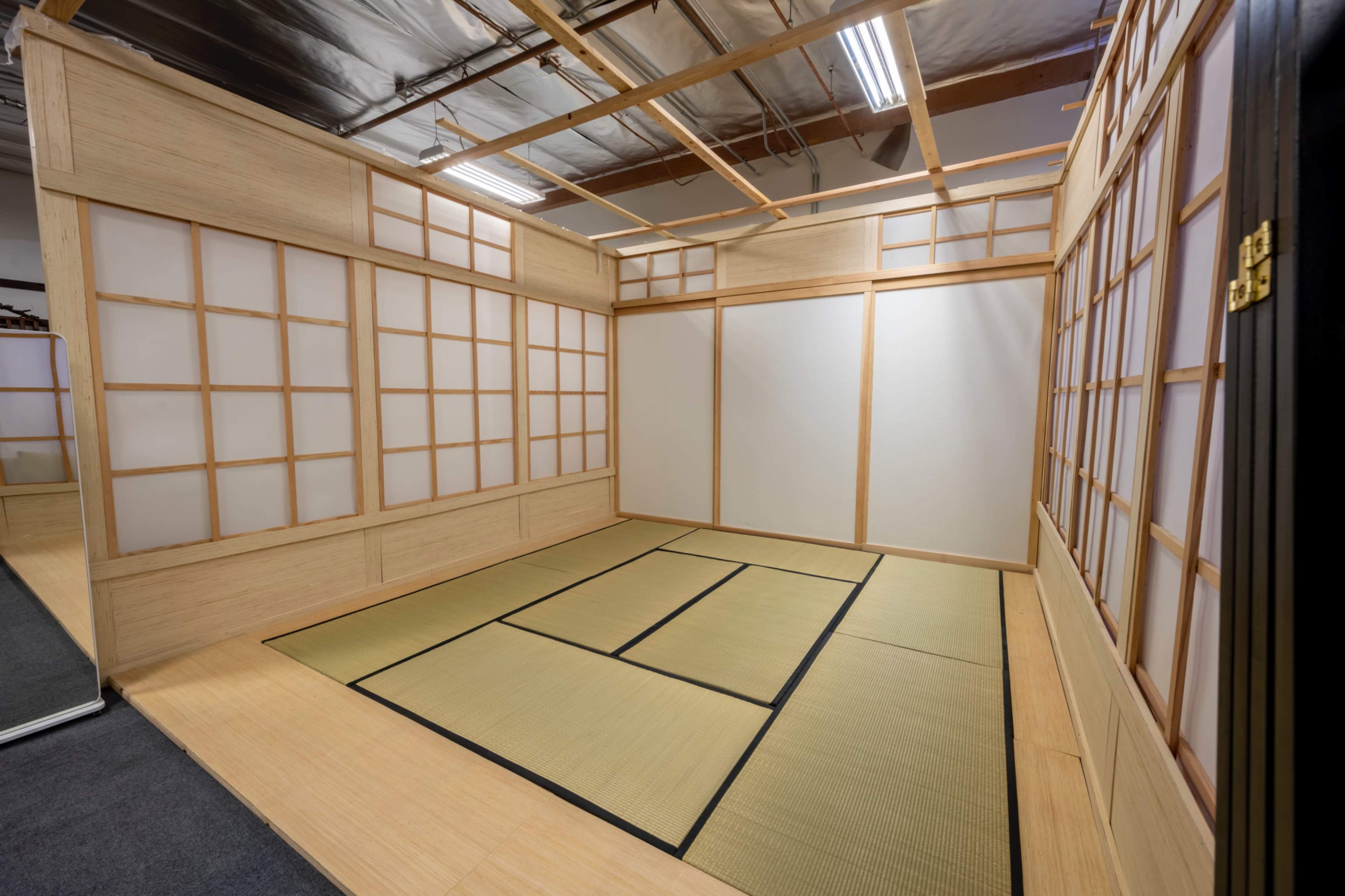A minimalist room with wooden walls, tatami flooring, and shoji screens.