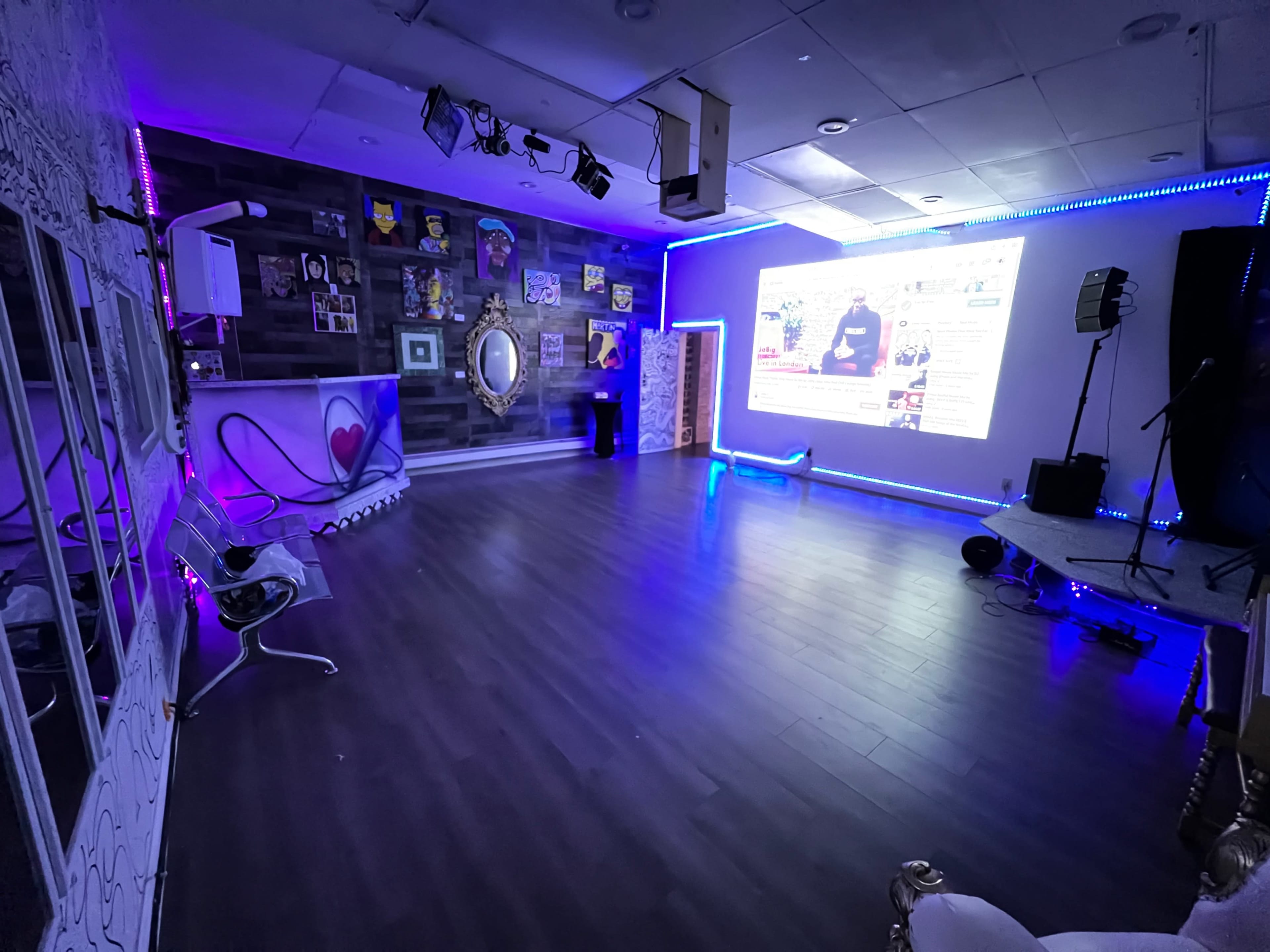 A spacious room with purple LED lights, a large screen displaying content, and various decorations on the walls.