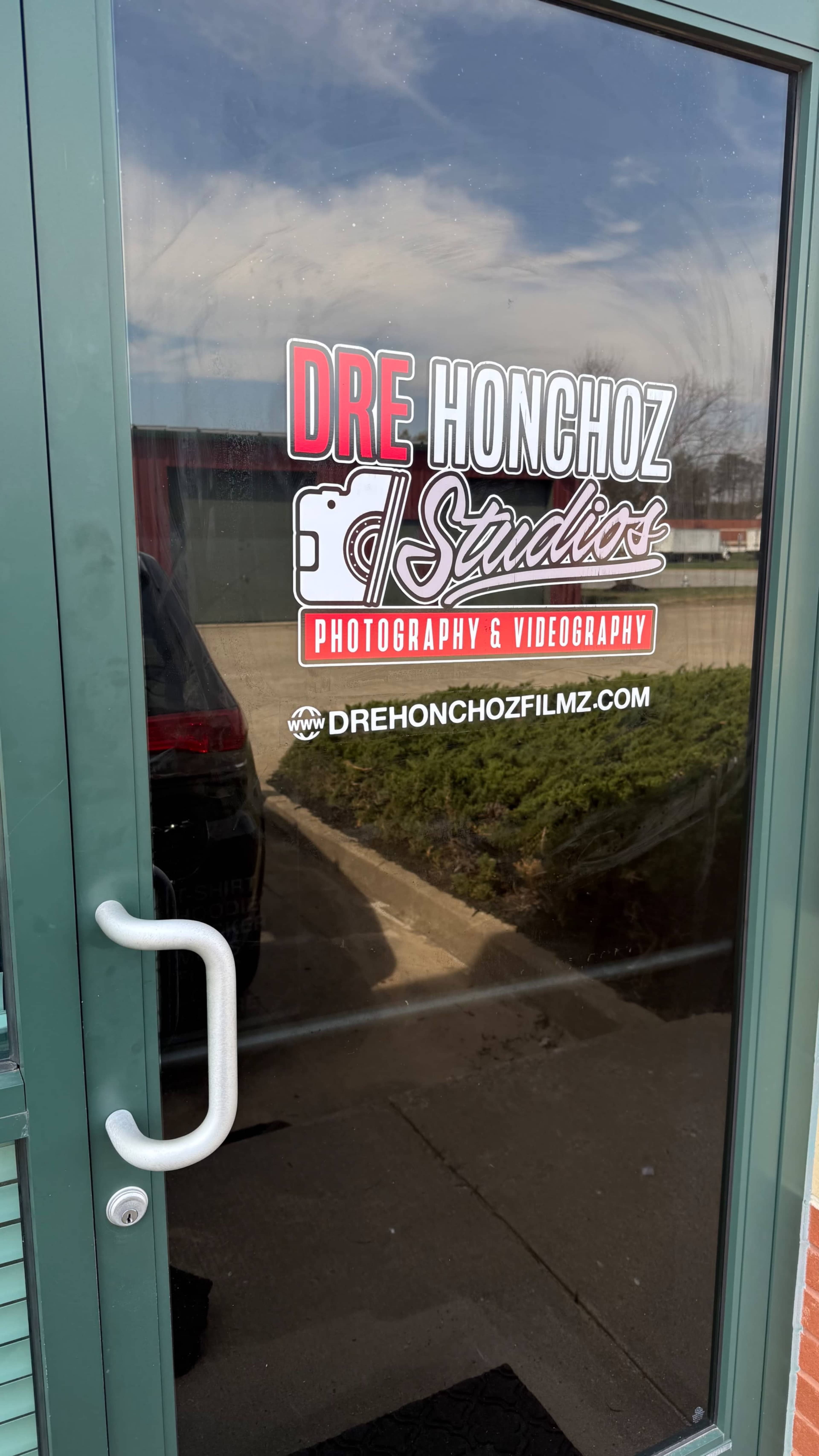A glass door displays a sign for "Dre Honchoz Studios" specializing in photography and videography.