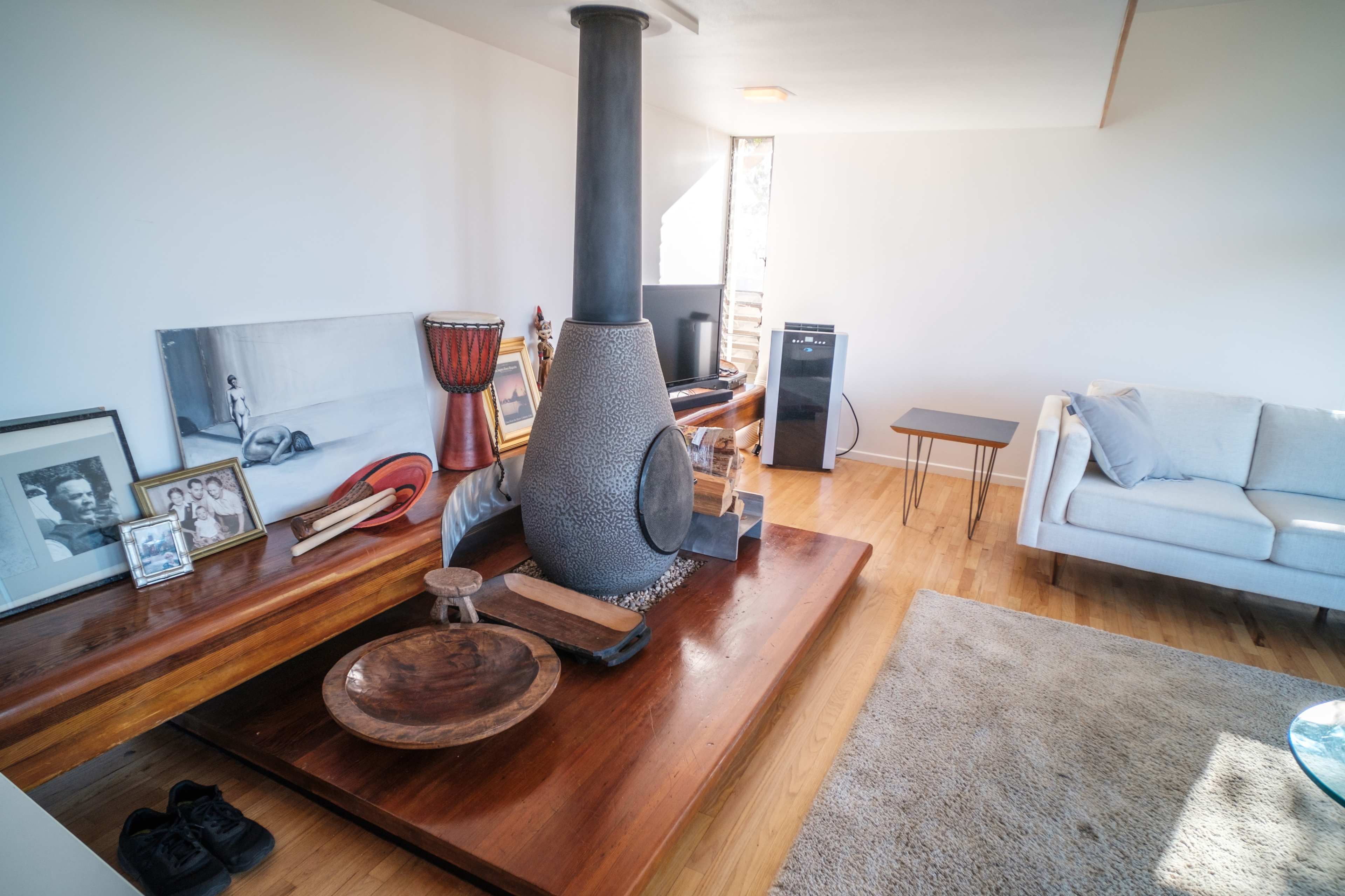 A modern living room with a central fireplace, wooden furniture, and a light-colored sofa.