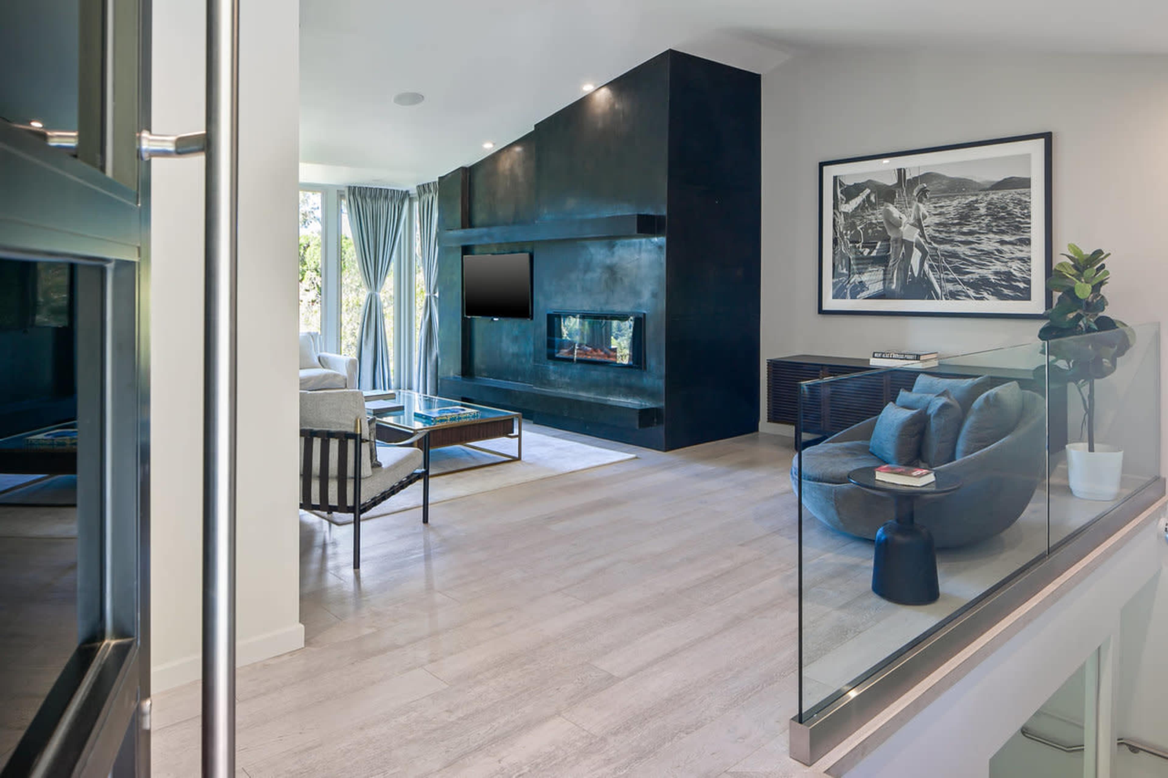 A modern living room featuring a large black feature wall with a fireplace, a television, and a gray sofa set.