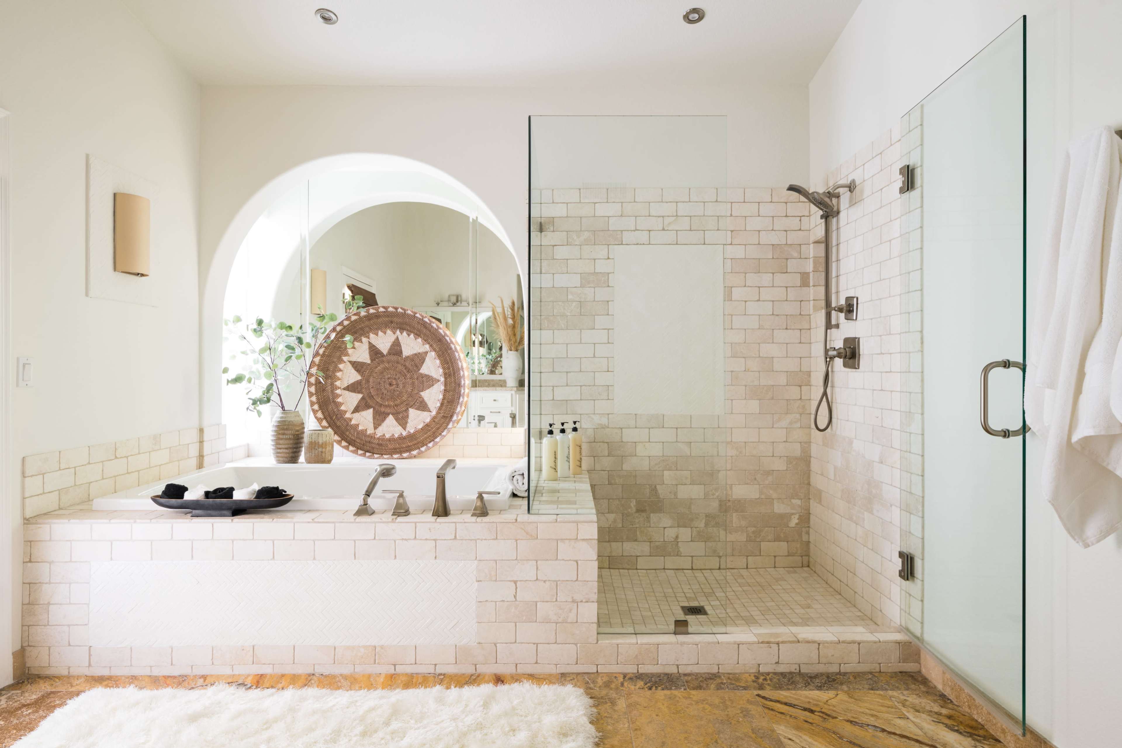 A spacious bathroom features a tiled shower area, a large bathtub with decorative elements, and a window that allows natural light to illuminate the space.