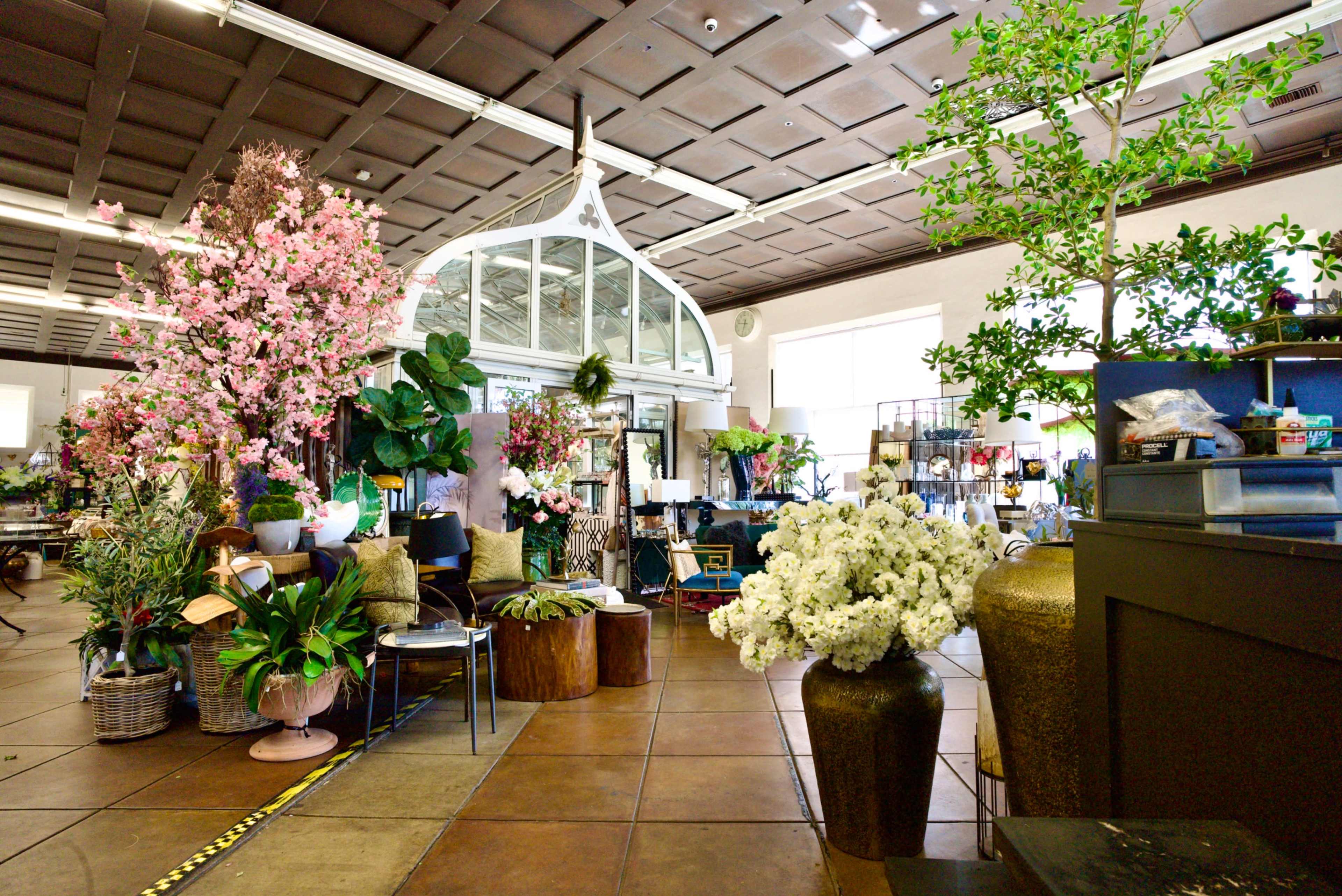 The image shows a spacious floral shop filled with various plants, flowers, and decorative items arranged throughout the area.