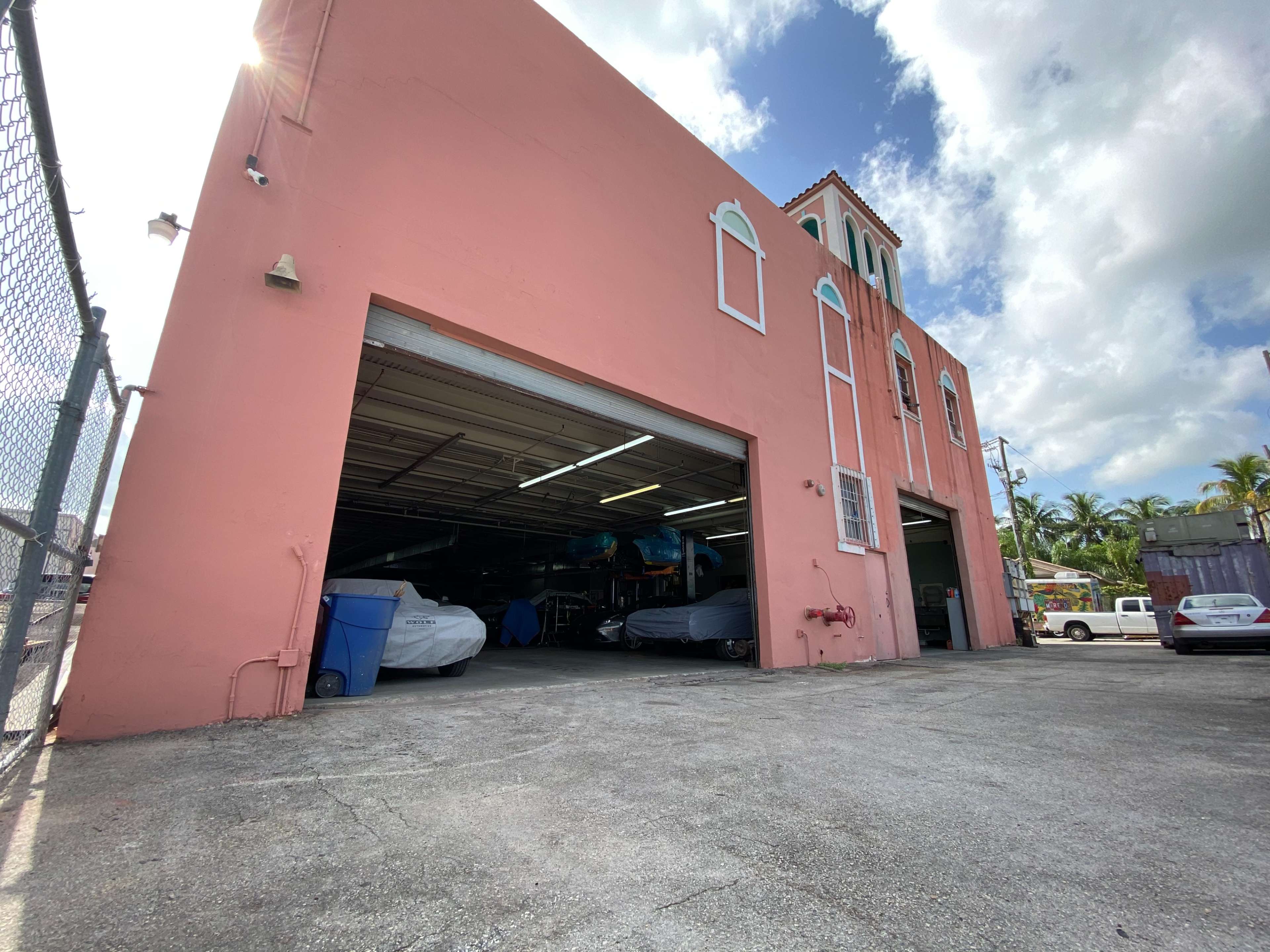 The image shows a pink commercial building with a garage door on the front, partially revealing boats inside.
