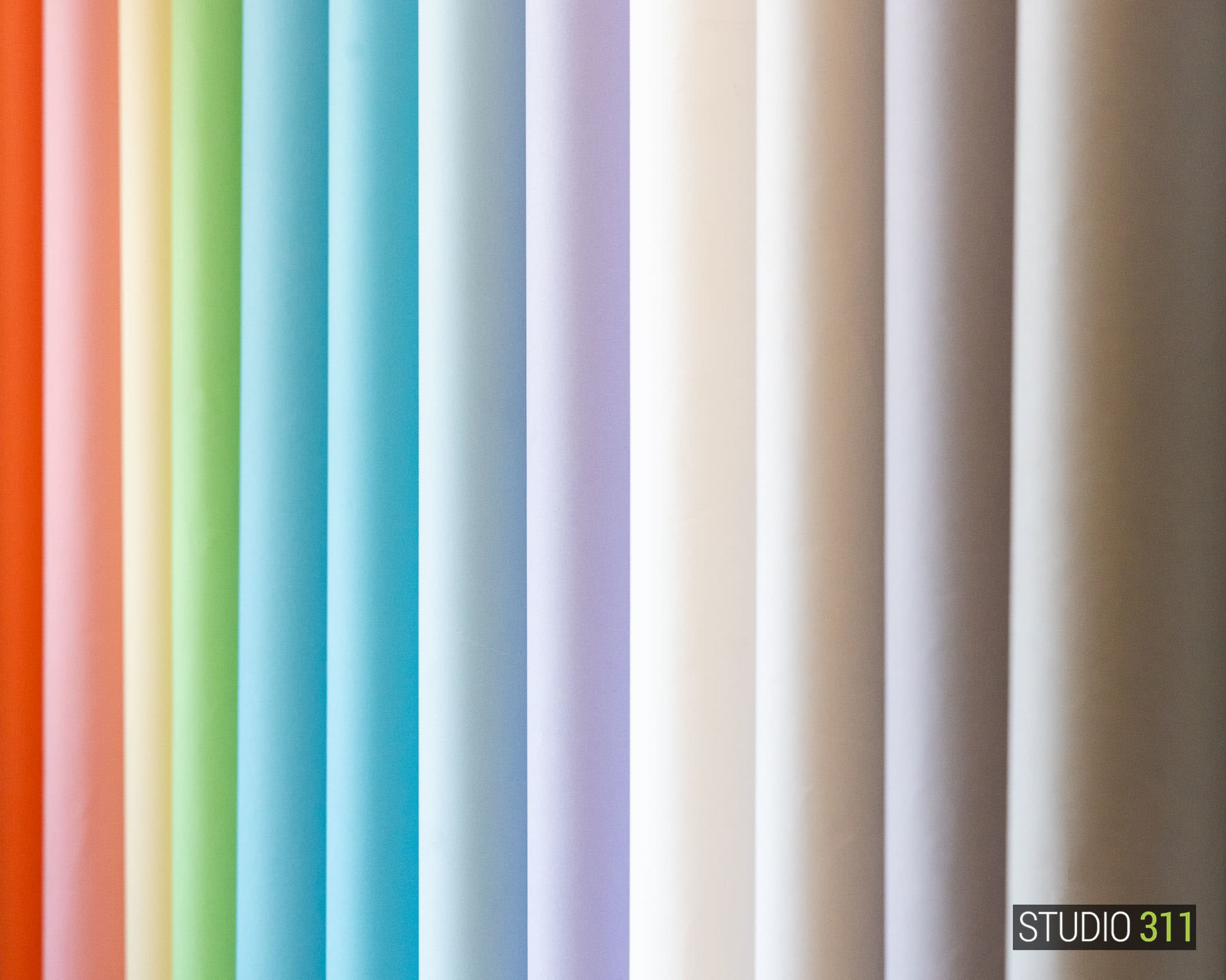 The image shows a vertical arrangement of colorful rolls of paper in various shades from orange to white.