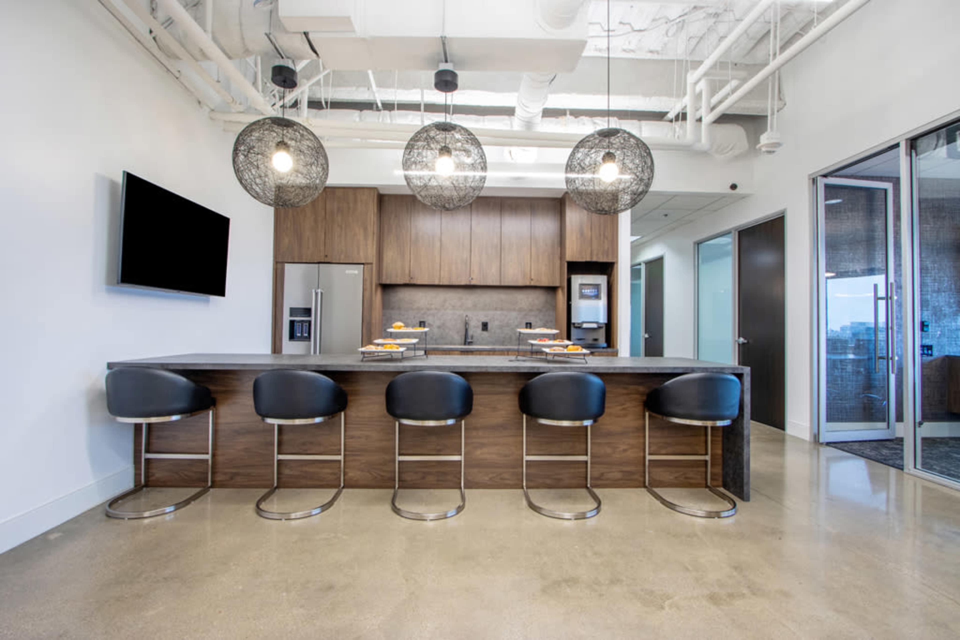 The image shows a modern kitchen with a central island, high stools, and pendant lighting above the counter.