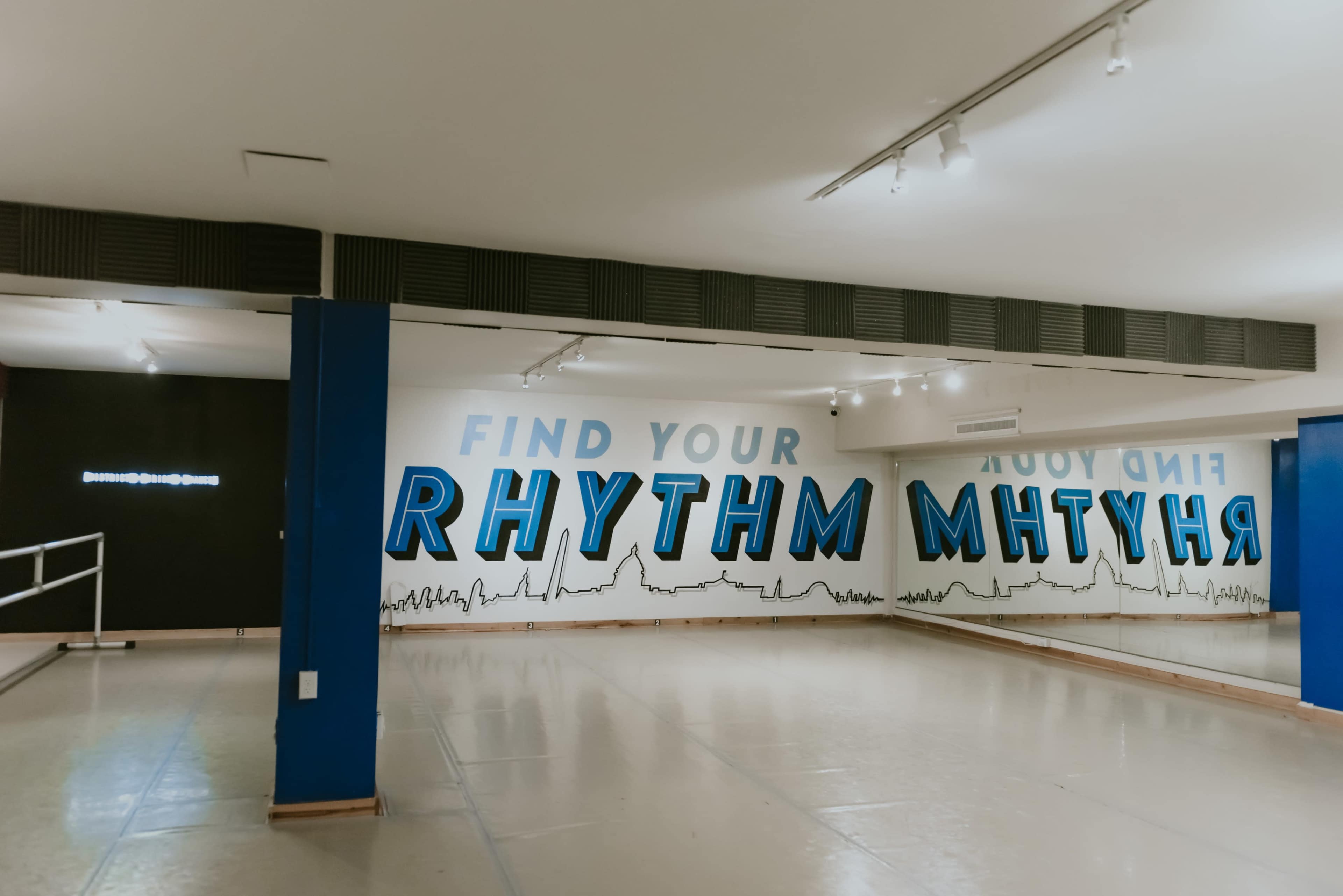 A dance studio with a mirrored wall and a mural that reads "FIND YOUR RHYTHM."