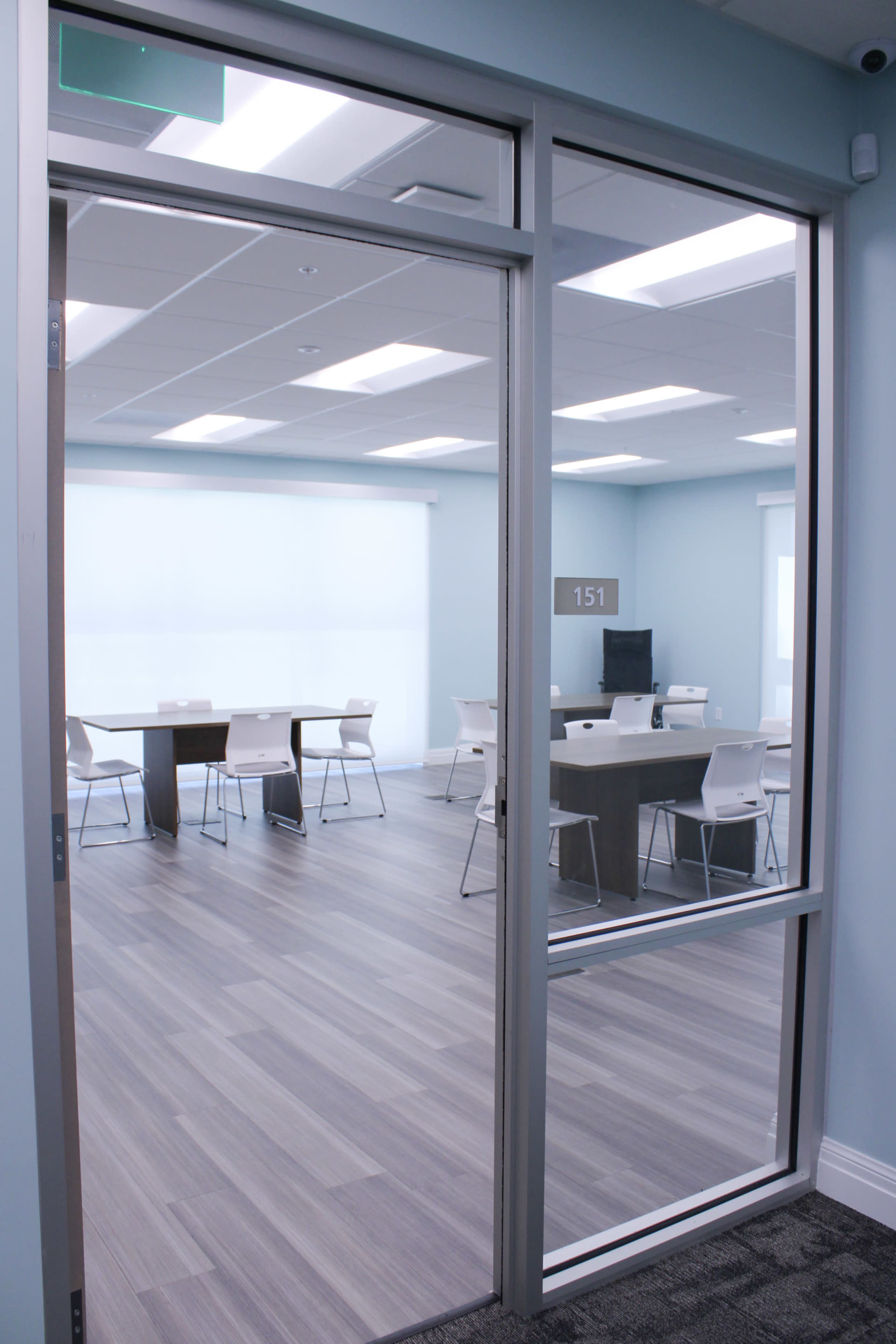 An interior view of a conference room with several tables and chairs, visible through a glass door.