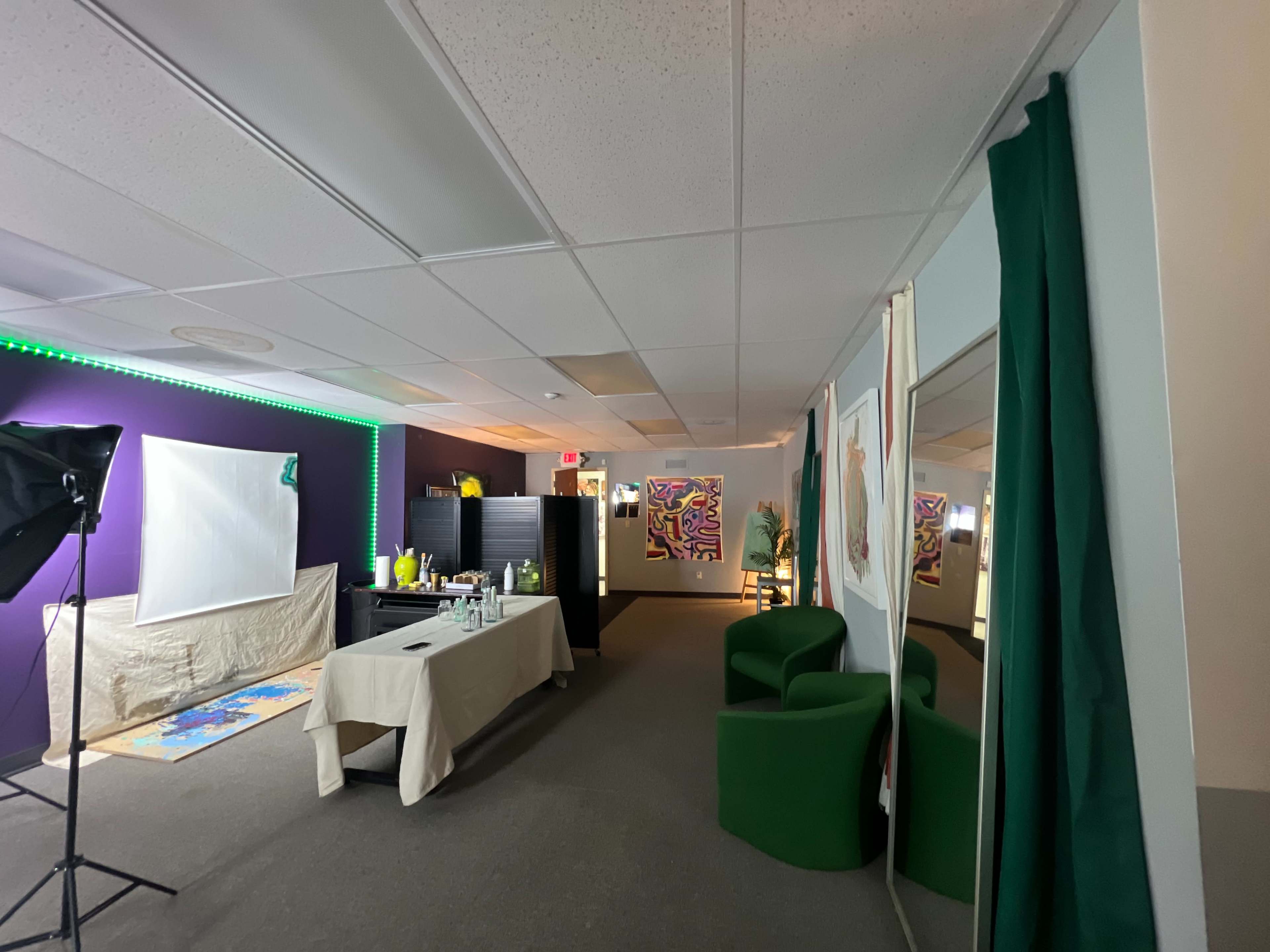 A modern office space with green furniture, a table set up with various items, and colorful artwork displayed on the walls.