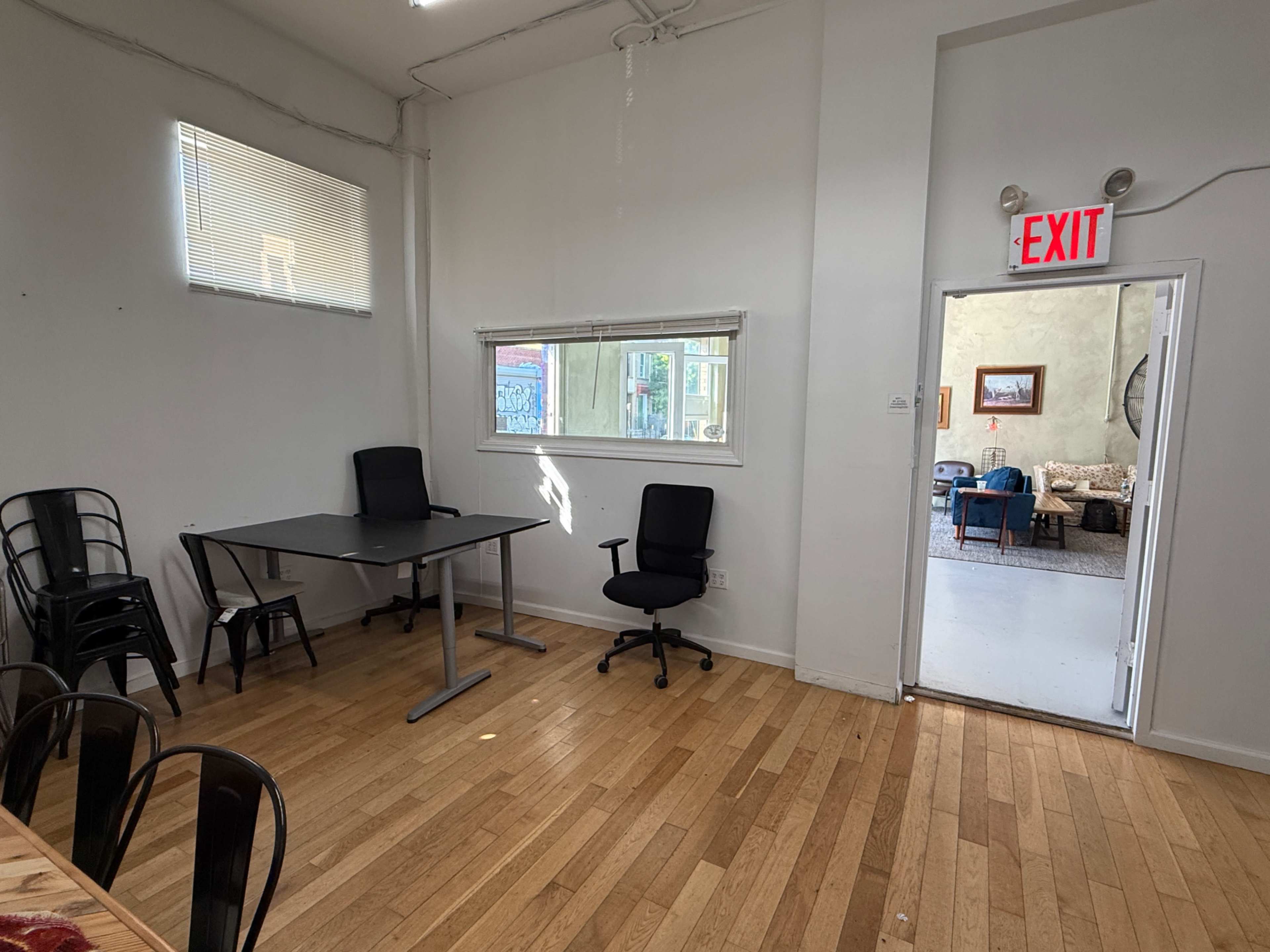 The image shows a bright, empty room with a table and chairs on one side and a doorway leading to another area on the right.