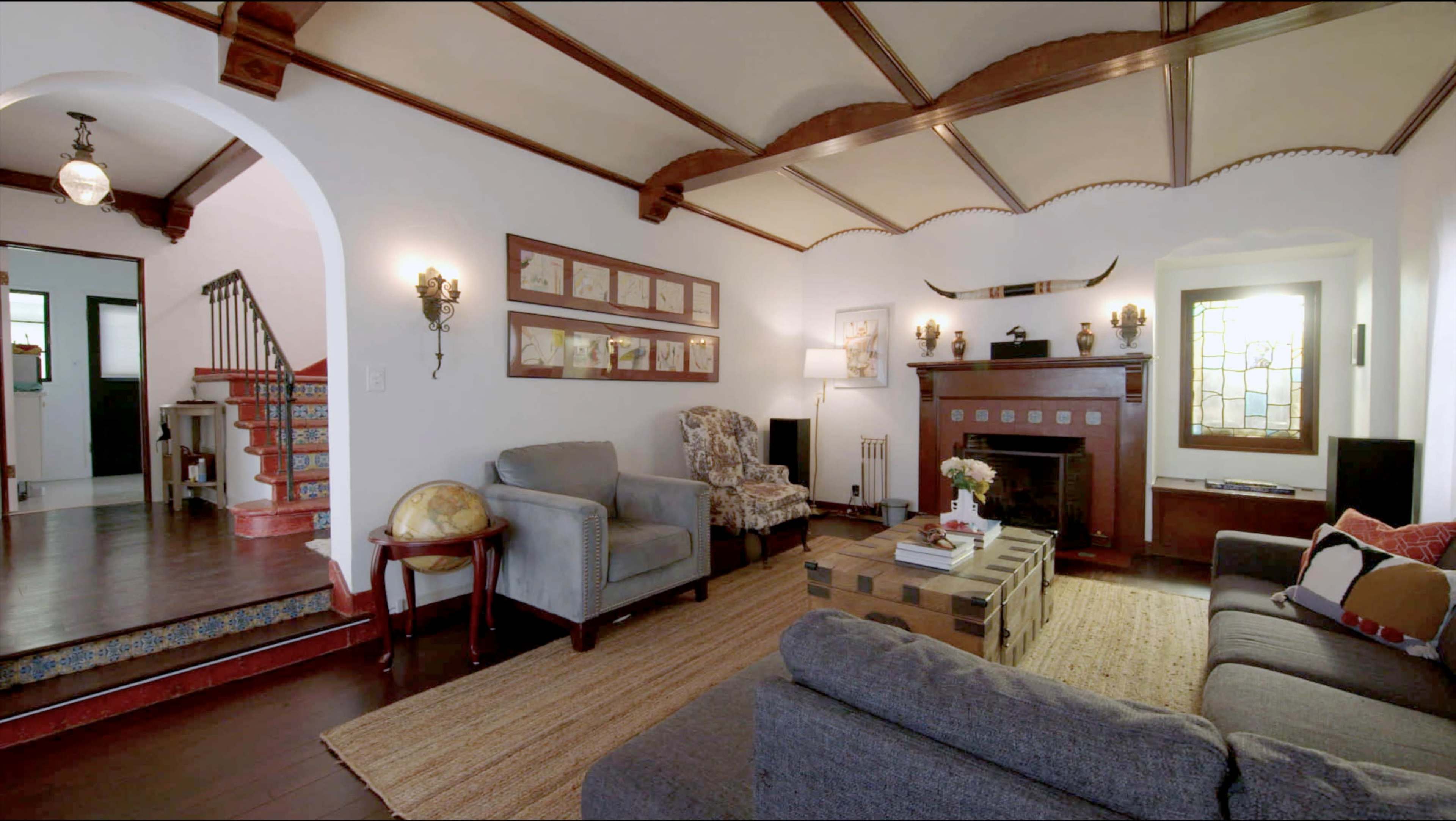 A cozy living room features two sofas, an armchair, a coffee table on a textured rug, and a fireplace adorned with decorative elements.