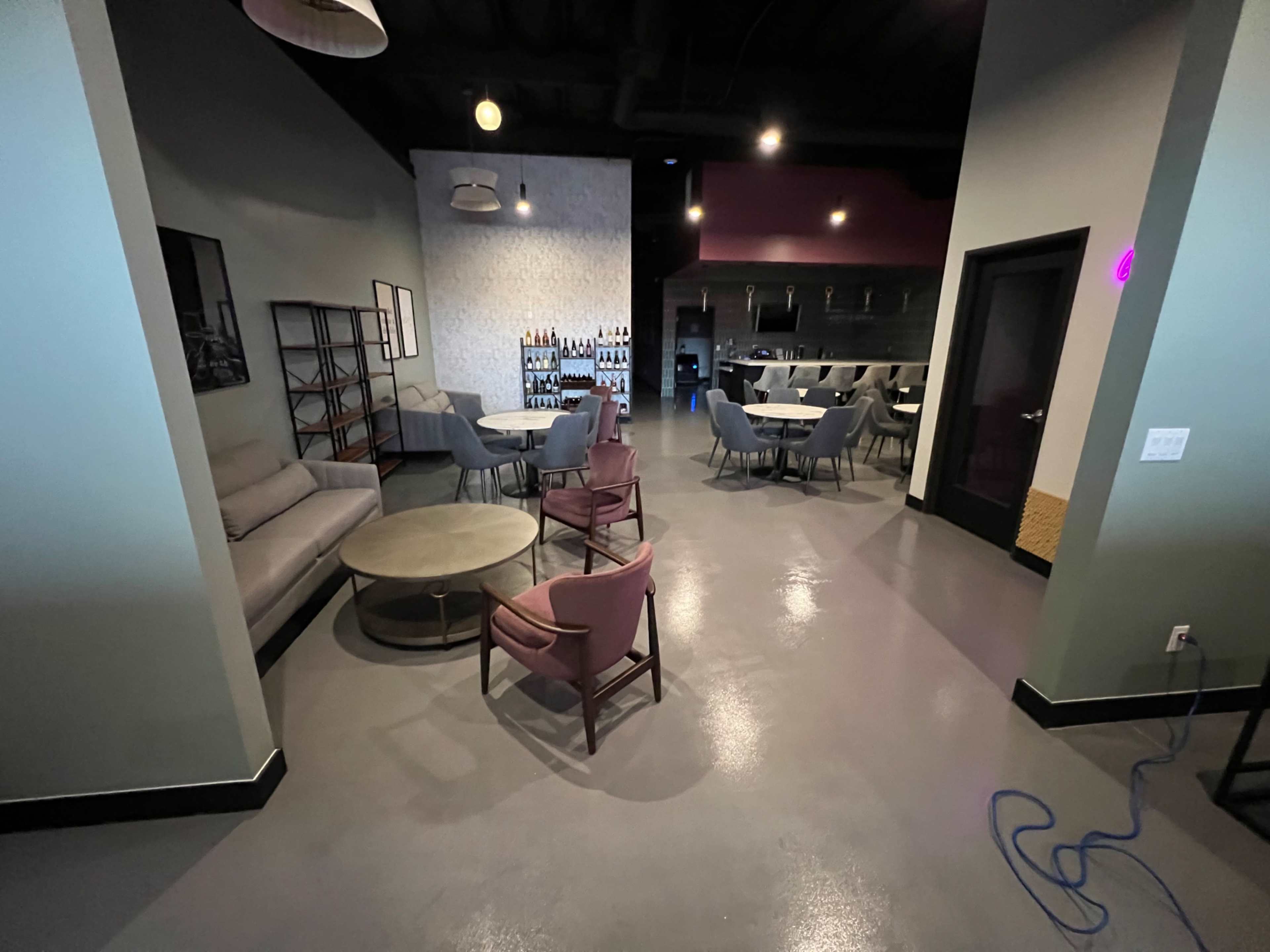 The image shows a modern interior space with a seating area featuring a couch and chairs, and a bar area in the background.