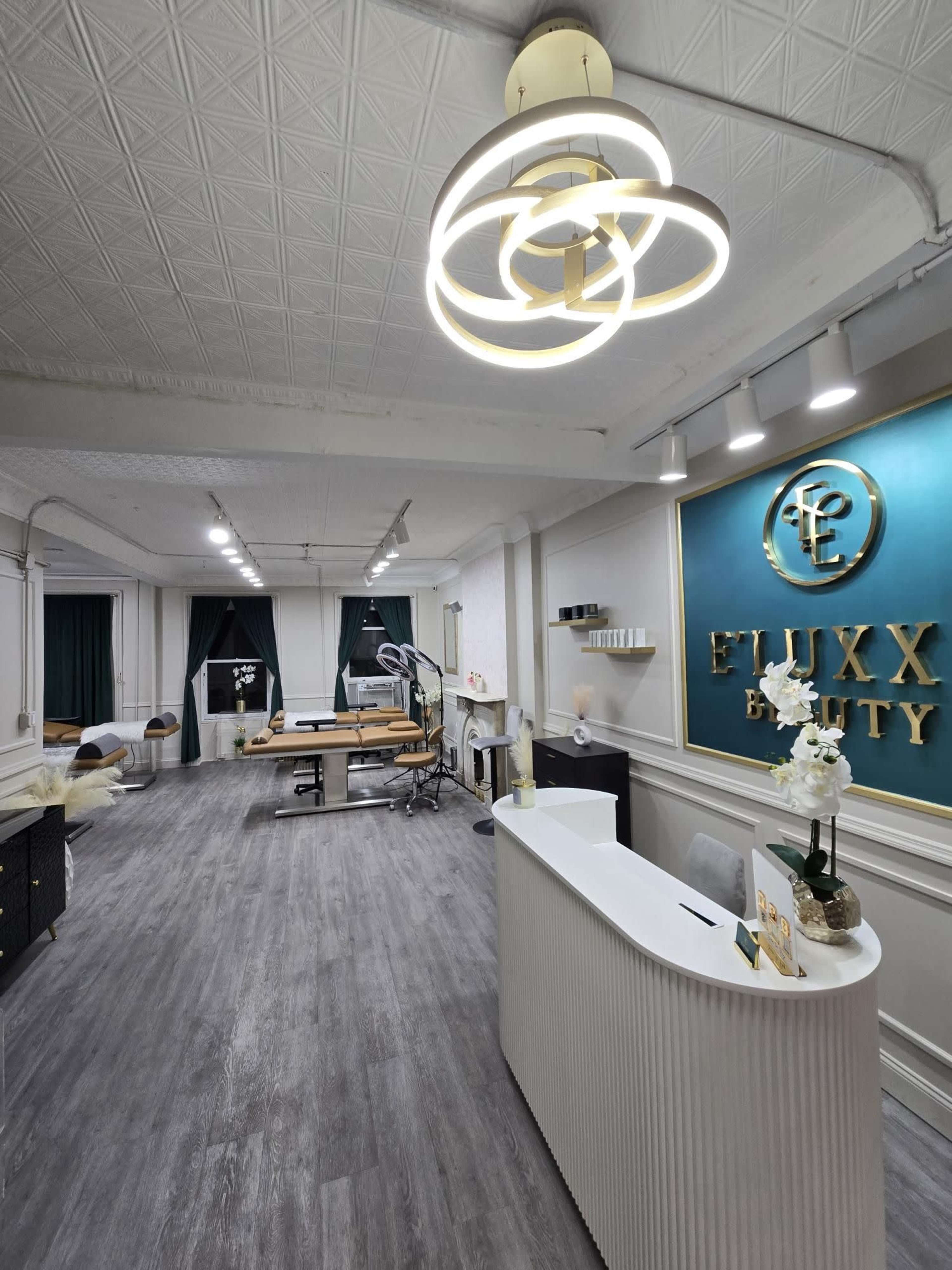 The image showcases a modern beauty salon interior featuring a reception desk, treatment area, stylish lighting, and elegant decor elements.