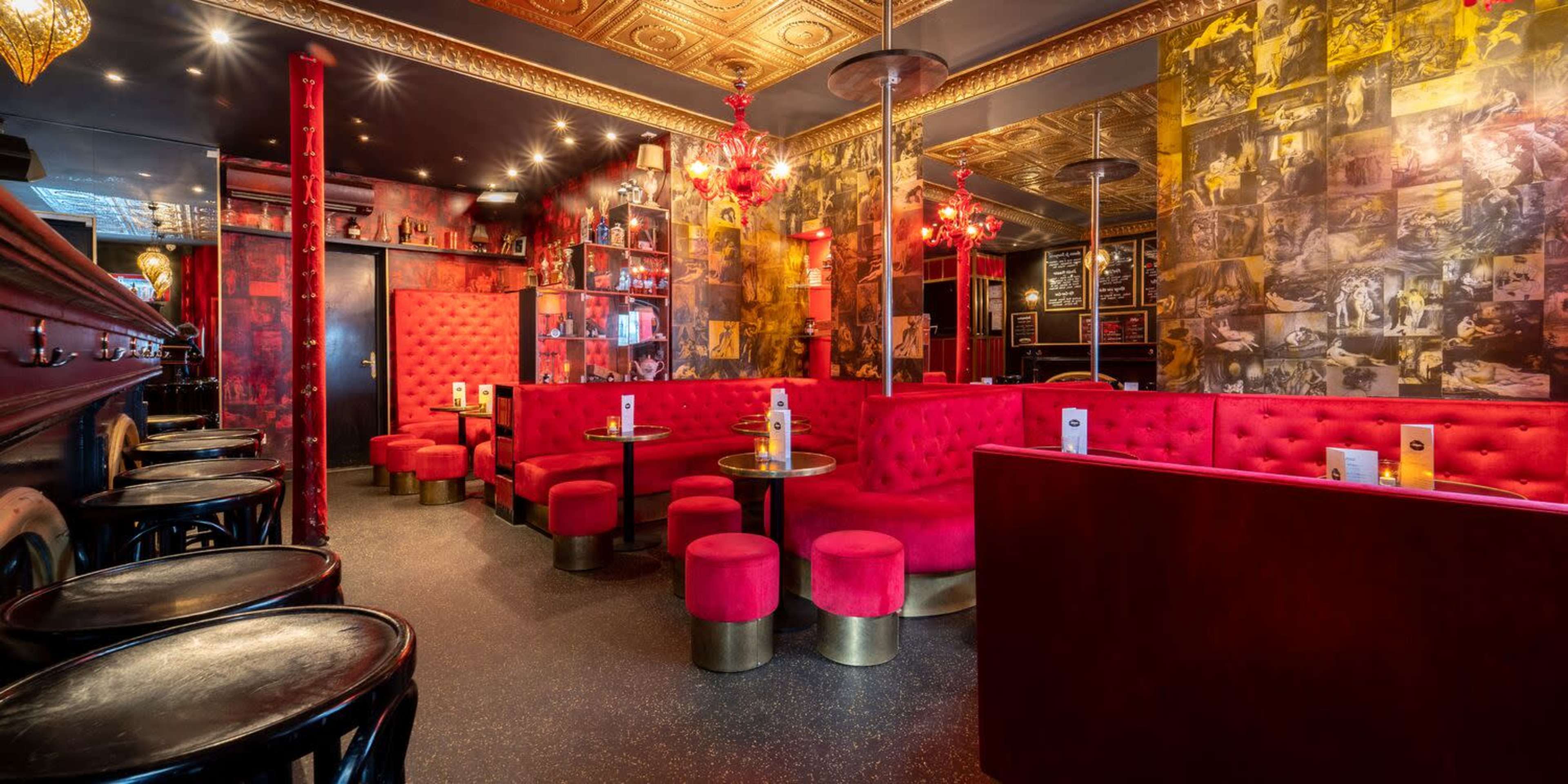 A stylish bar interior featuring red velvet seating, golden accents, and a wall decorated with vintage photographs.