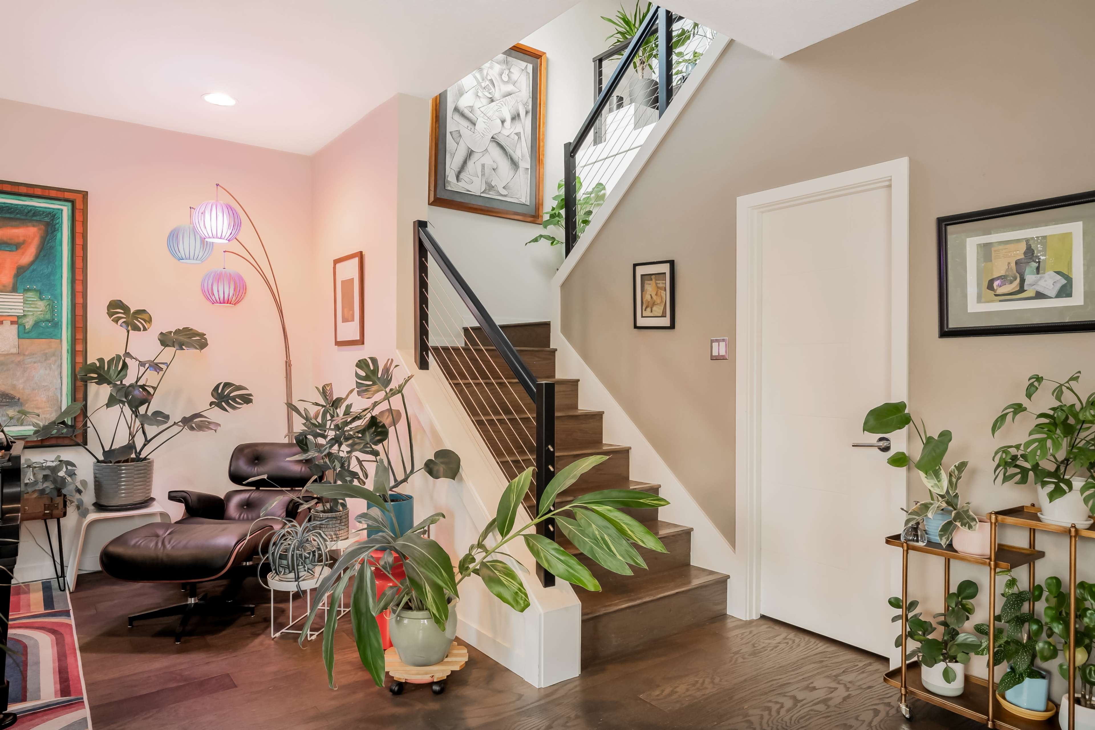 A well-lit entryway with a staircase, a seating area adorned with plants, and framed artwork on the walls.