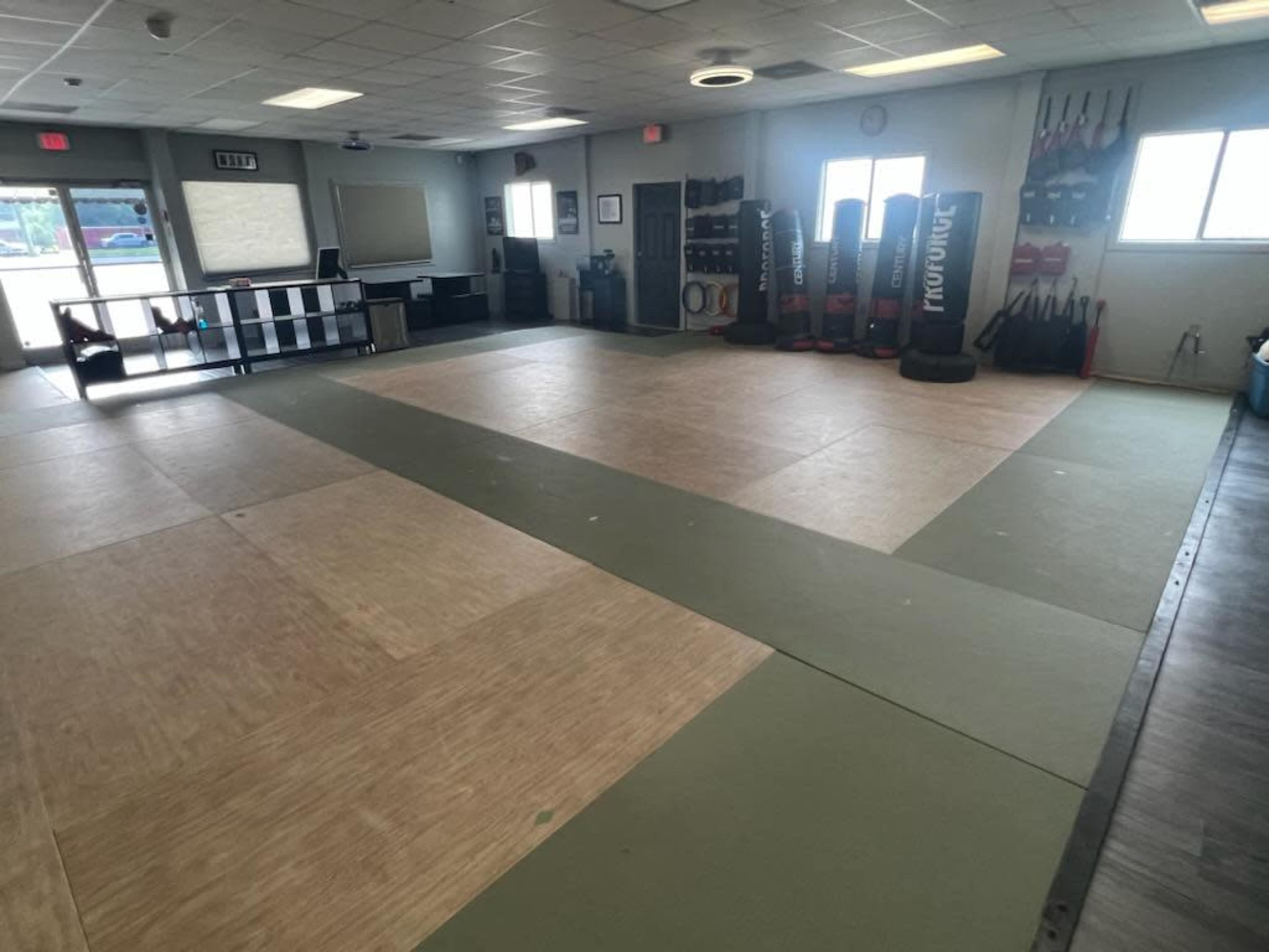 An empty training room with padded flooring and exercise equipment lined against the walls.