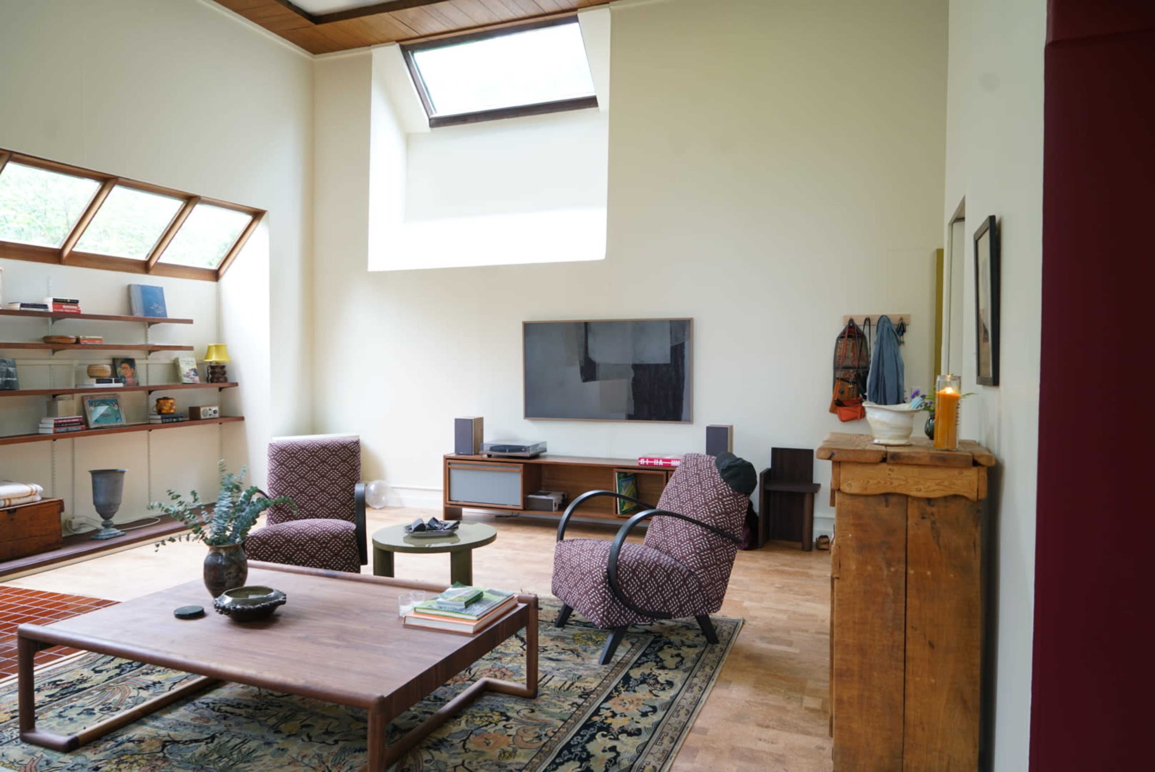 A modern living room with two patterned chairs, a wooden coffee table, and a large window letting in natural light.