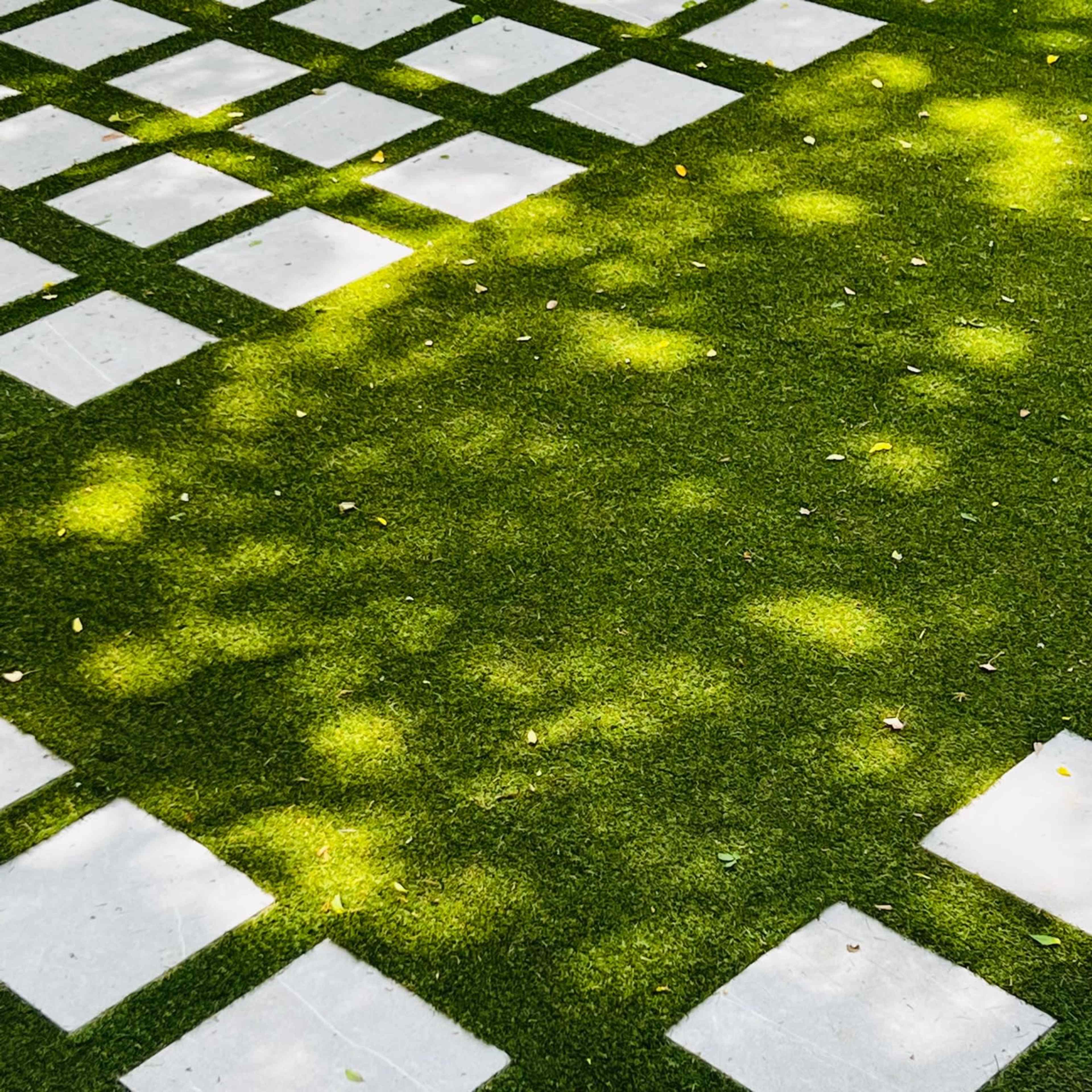 A lawn with square concrete tiles arranged on a grassy surface.