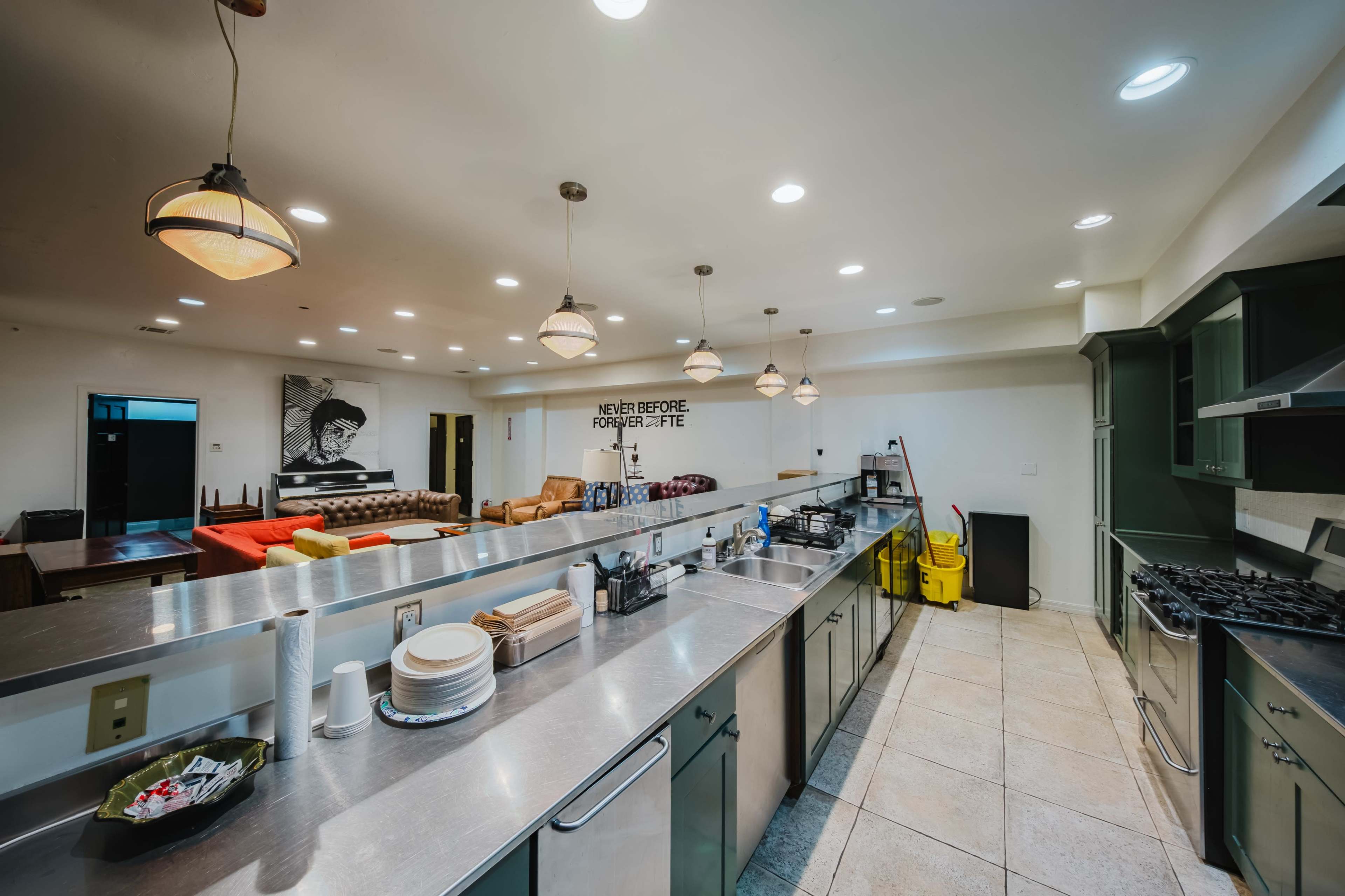 A modern kitchen features stainless steel countertops, colorful seating, and a clean, organized layout with ample lighting.