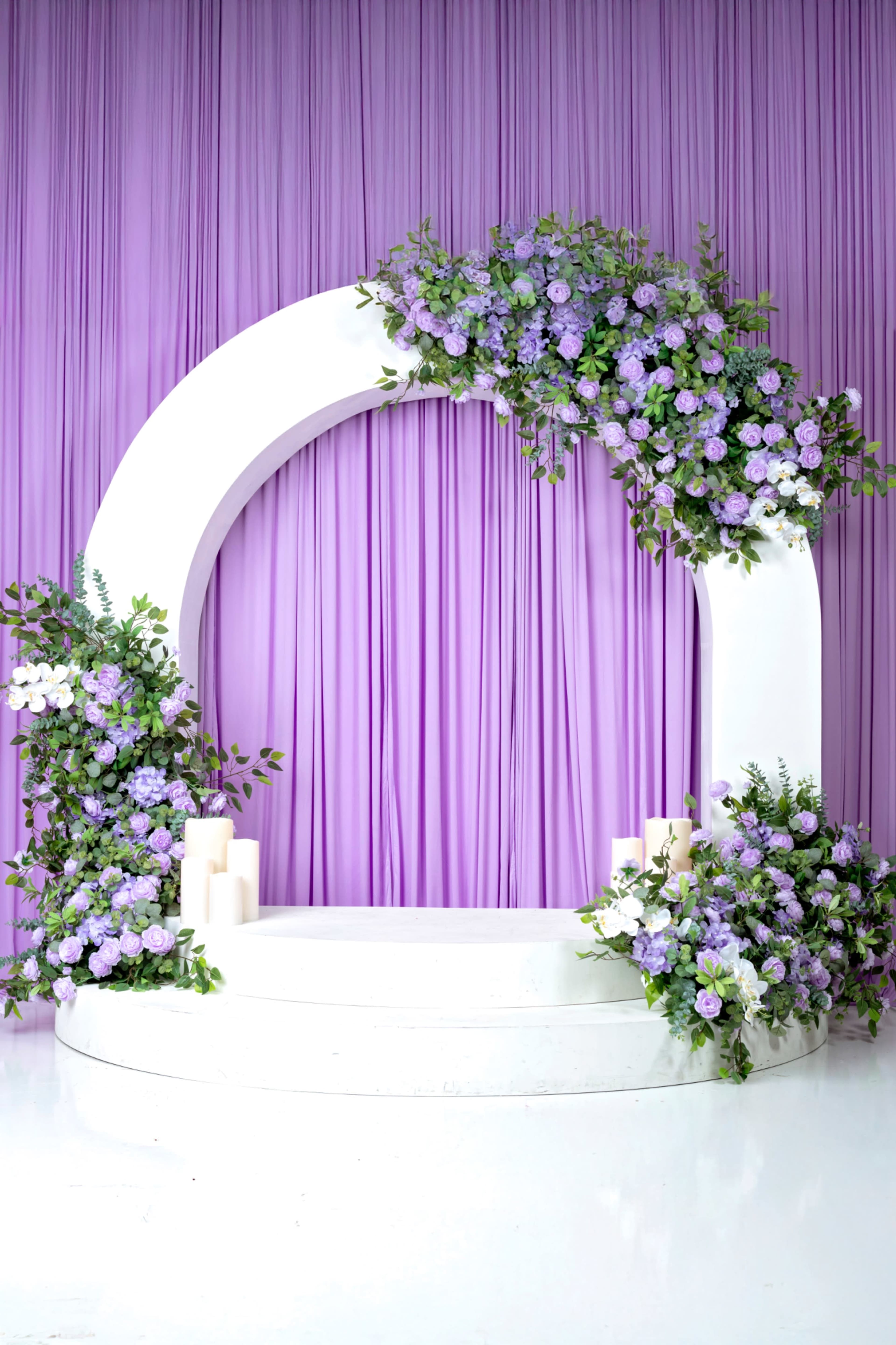 The image features a circular floral arch adorned with purple flowers, set against a backdrop of purple drapery.