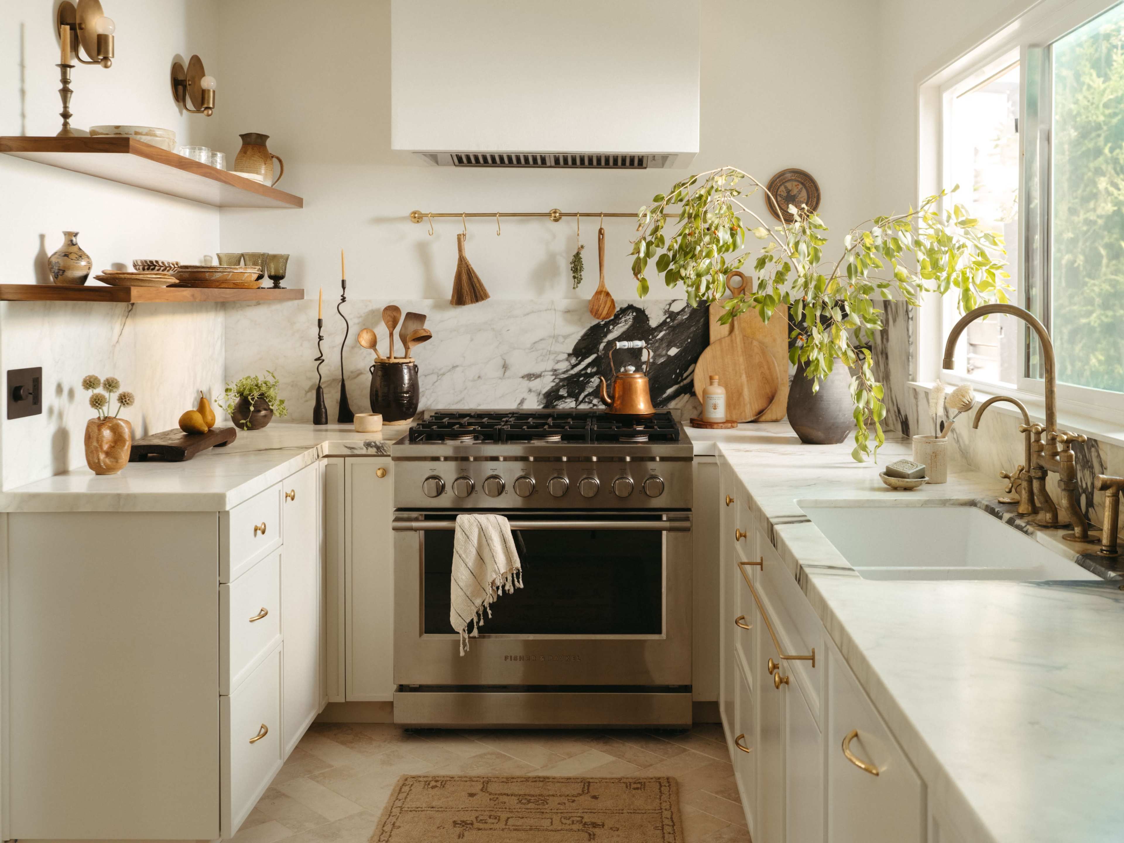 The image depicts a modern kitchen with marble countertops, wooden shelves holding various kitchen items, and a large stainless steel range oven.
