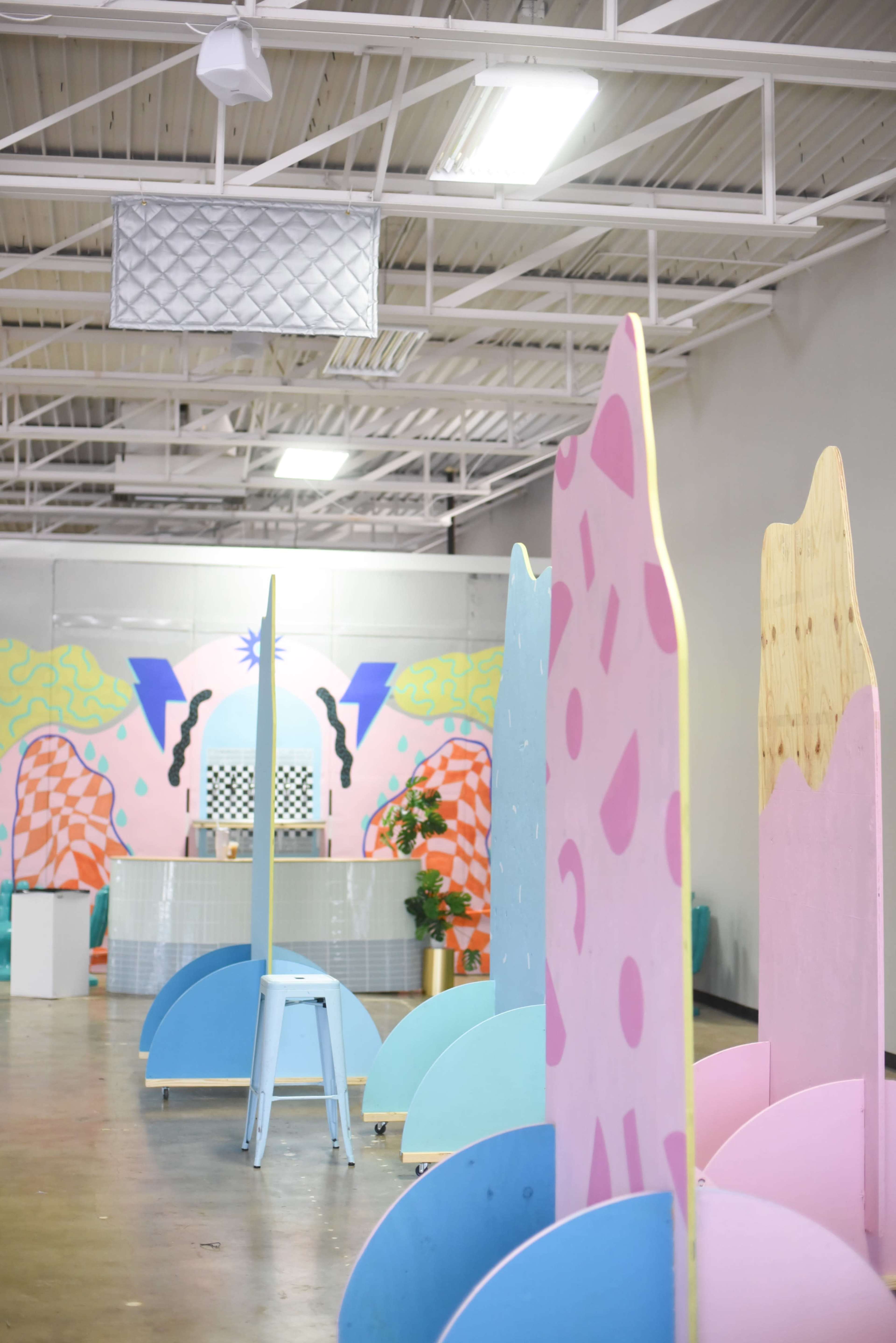 A spacious interior with brightly colored, abstract partition panels and a patterned backdrop featuring geometric designs.