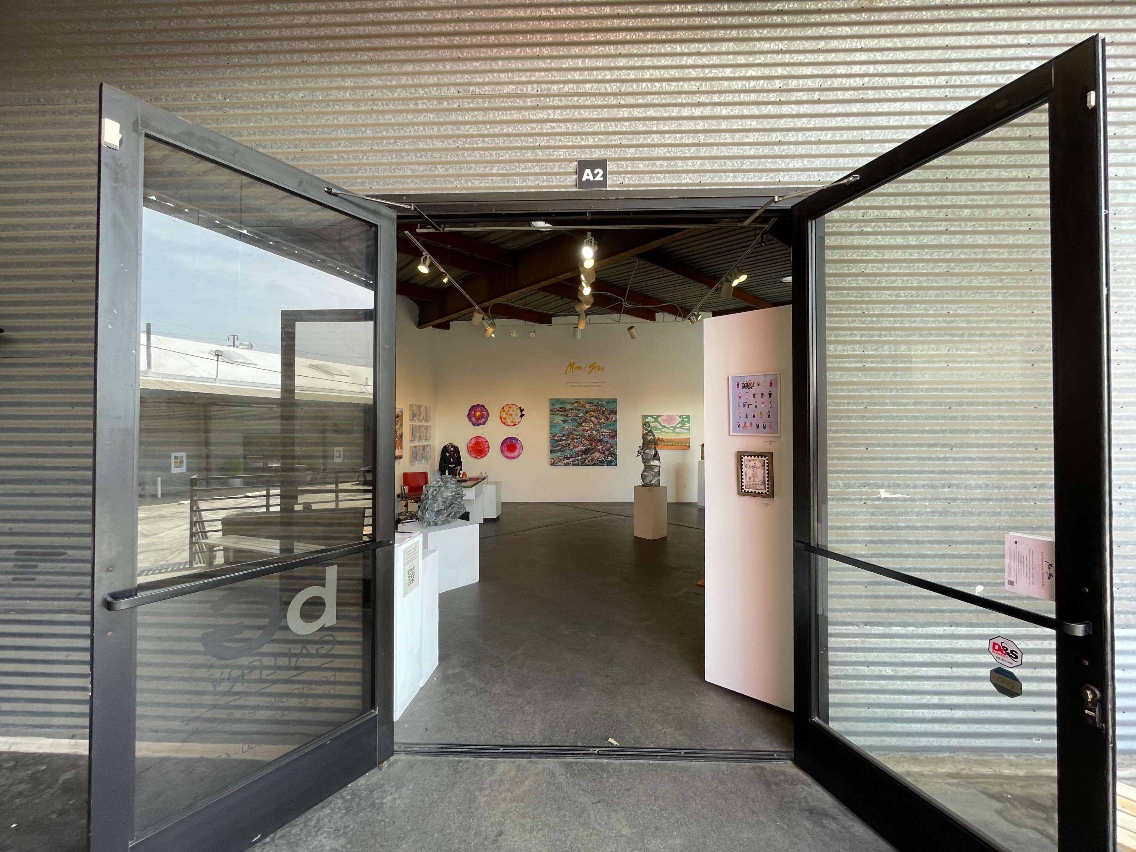 An open entrance to an art gallery featuring various artworks displayed on the interior walls.