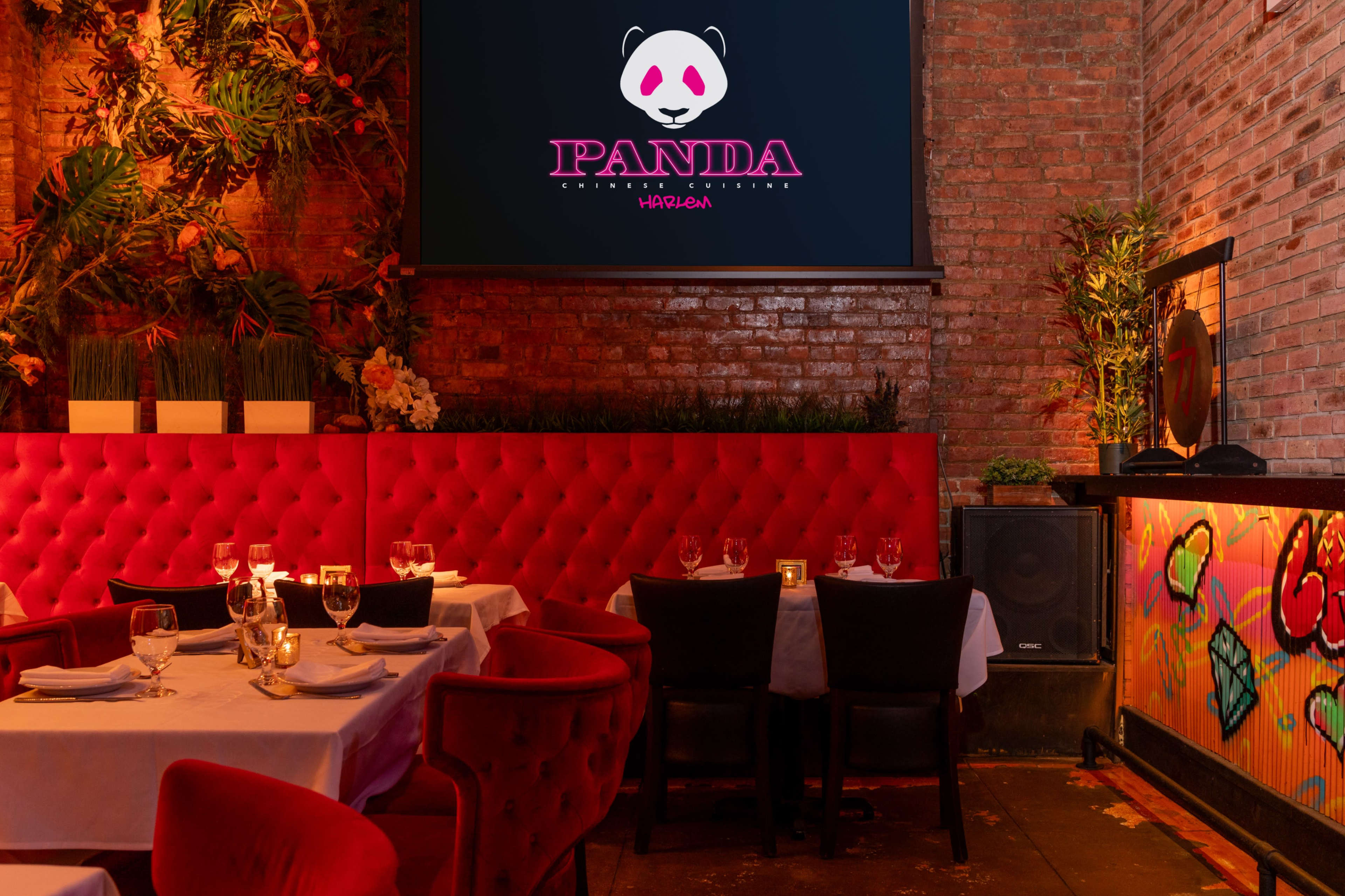 The image shows a stylish restaurant interior featuring red velvet seating, a large logo display, and tables set with white tablecloths and dinnerware.