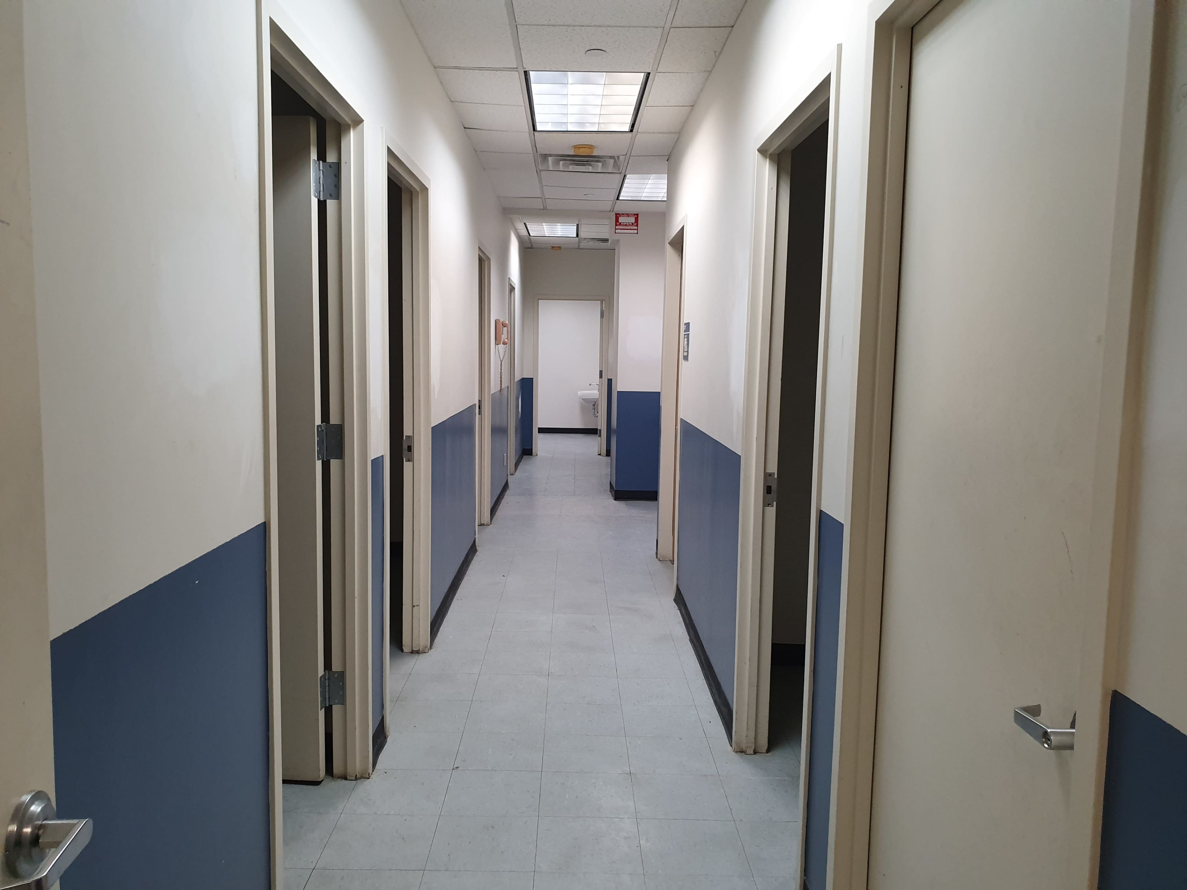 A long corridor with several doors on either side and a door at the end.