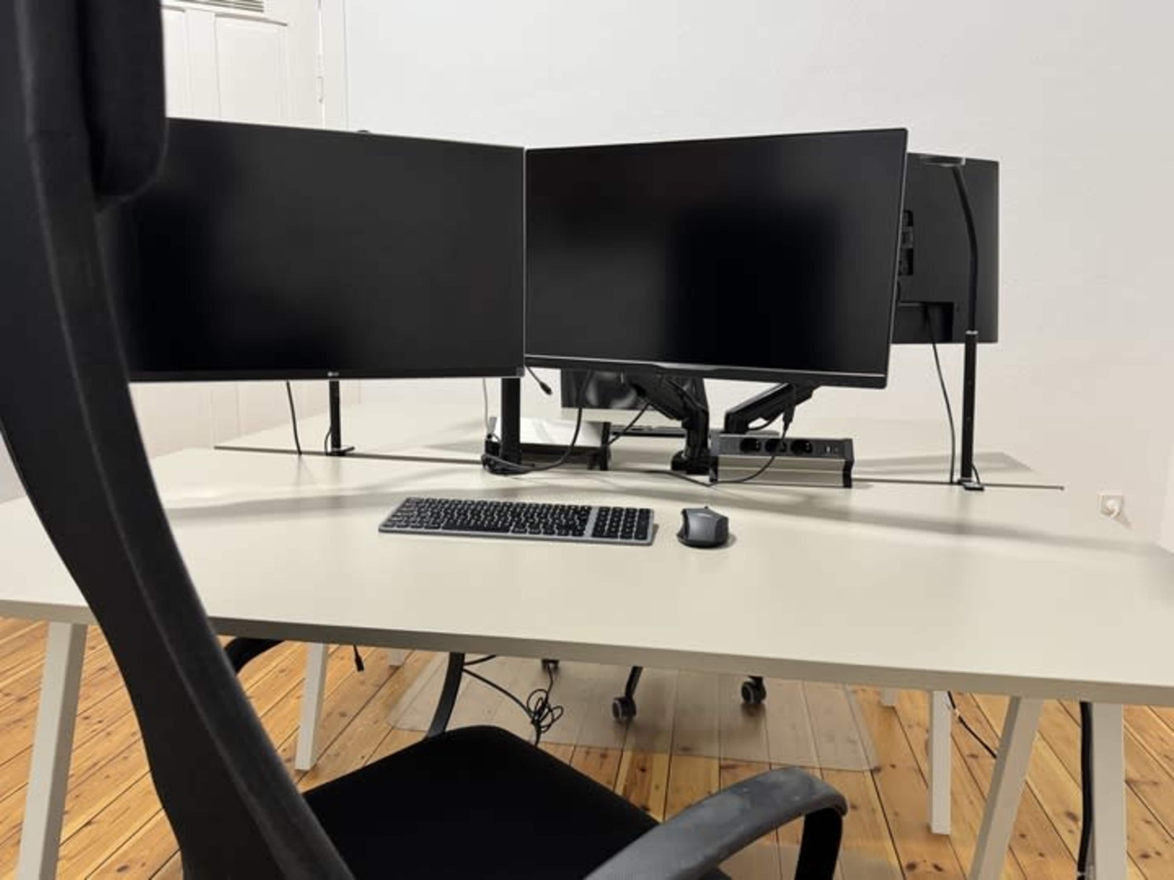 A modern workspace features a desk with two large monitors, a keyboard, and a mouse, accompanied by an ergonomic chair.