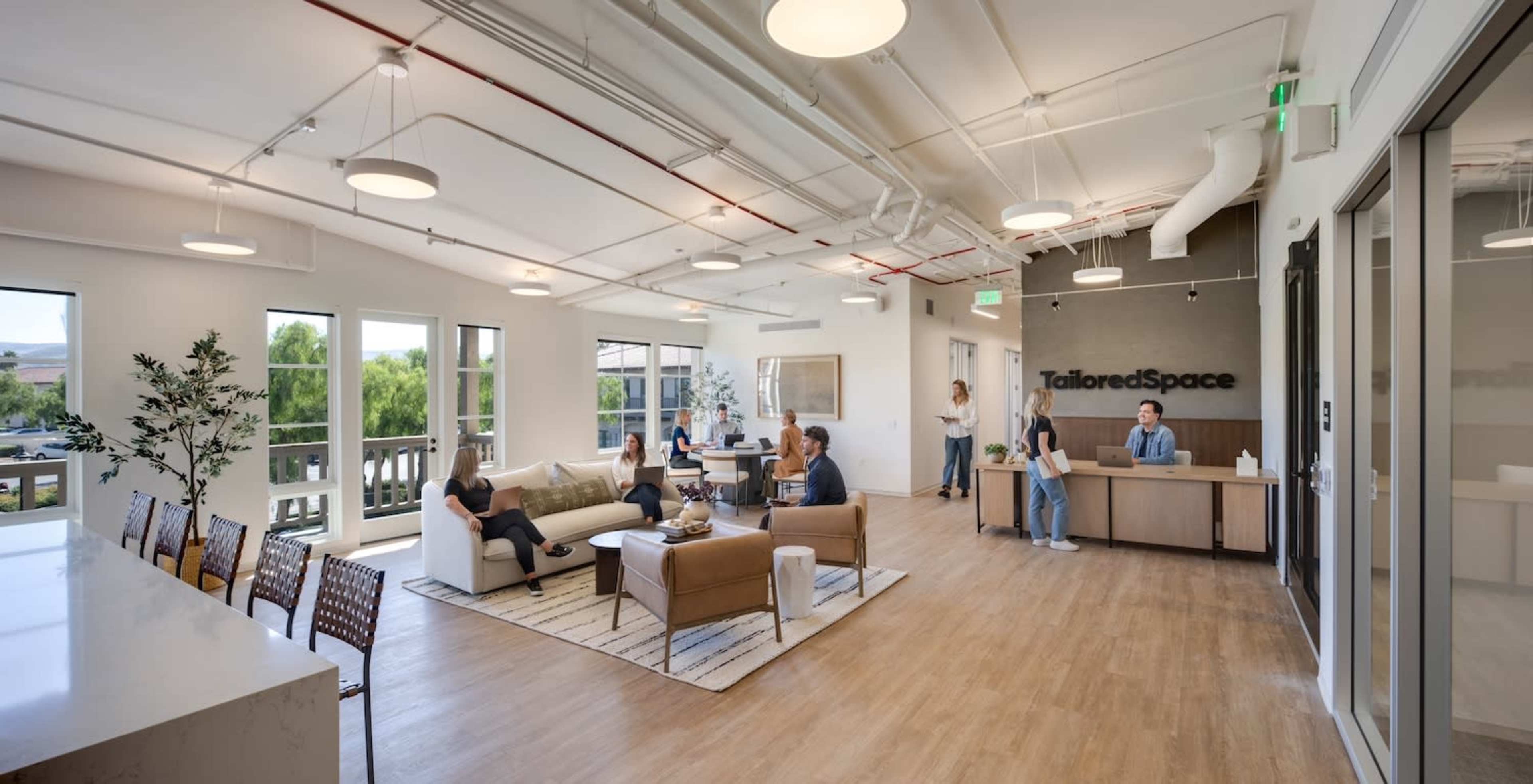 A modern office space with a reception area, seating arrangements, and several people engaged in various activities.